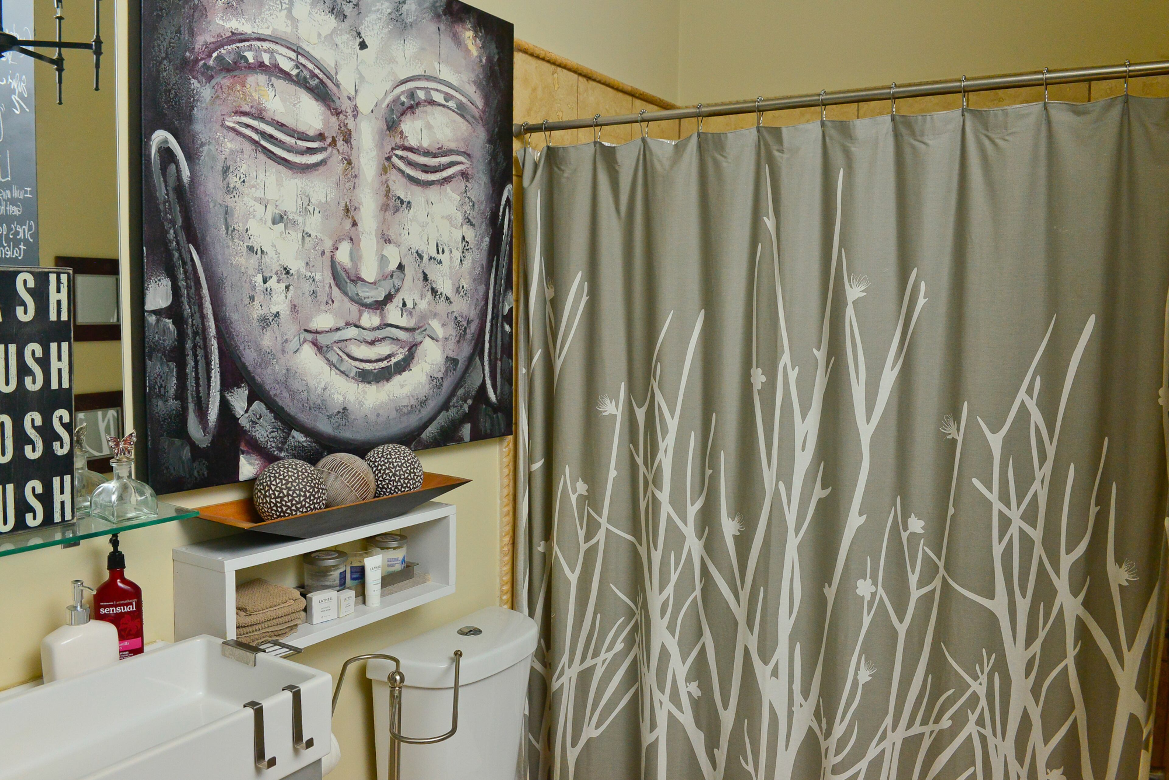 Artwork hangs throughout the 108-year-old renovated Craftsman home, including in the guest bathroom, where neutral tones, an organic woodland-themed shower curtain and a Buddha painting create a peaceful Zen-like retreat.