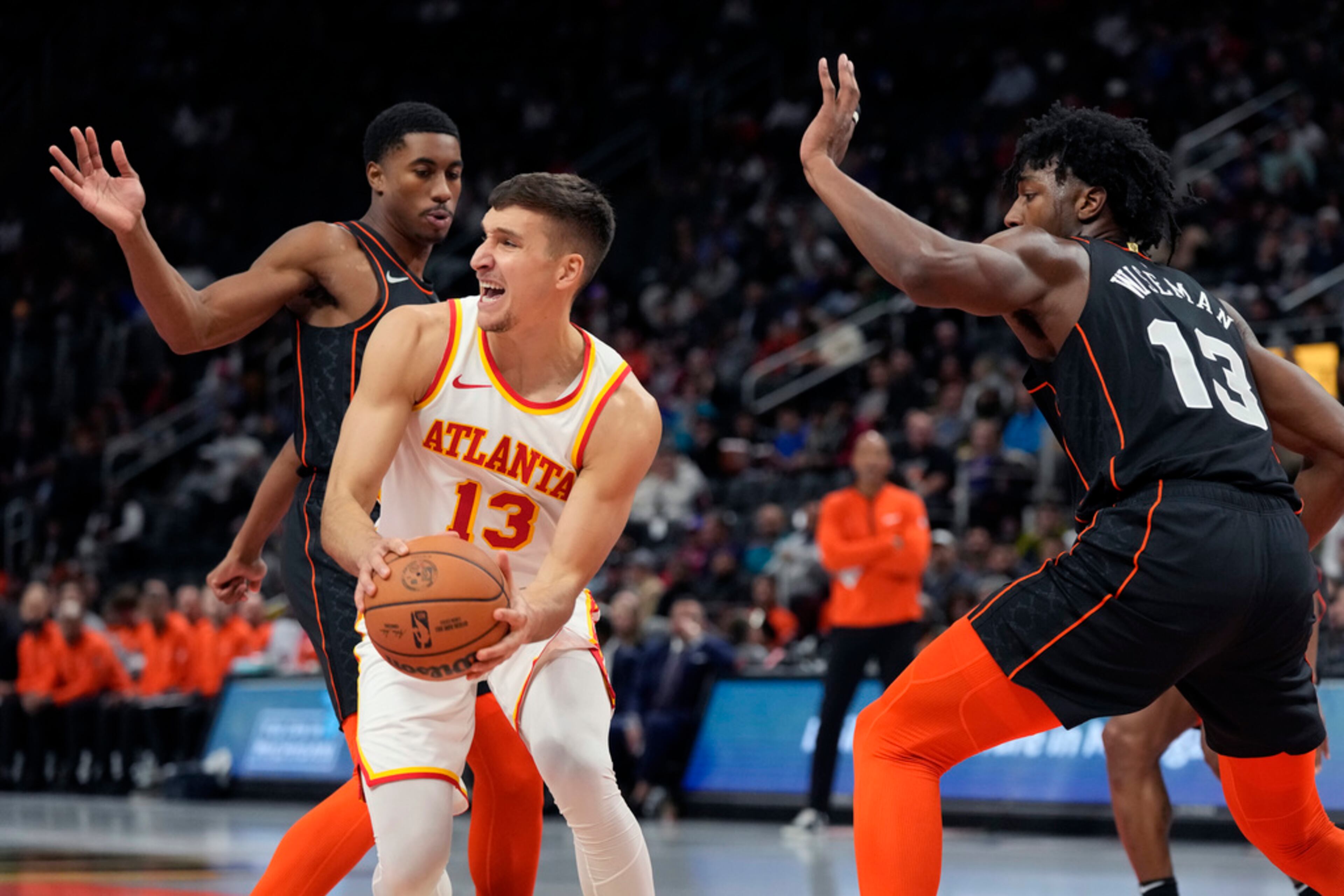 Atlanta Hawks guard Bogdan Bogdanovic (13) passes as Detroit Pistons guard Jaden Ivey, left, defends during the first half of an NBA basketball game, Tuesday, Nov. 14, 2023, in Detroit. (AP Photo/Carlos Osorio)