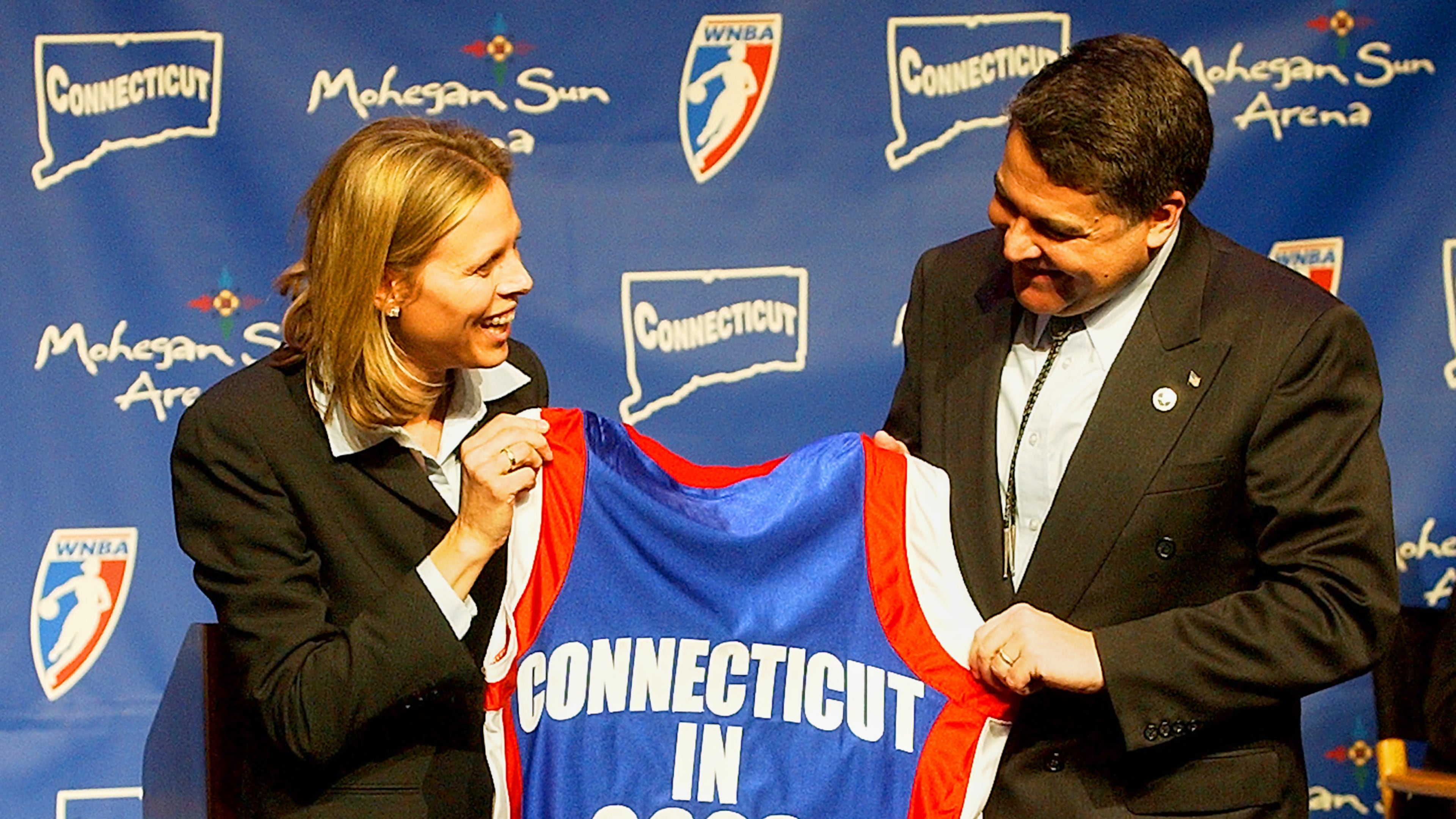 FILE - WNBA League President Val Ackerman, left, and Mohegan Tribe Tribal Chairman Mark Brown hold a basketball shirt of the type that will be worn by the WNBA team Connecticut Sun during a news conference Tuesday, Jan. 28, 2003, at the Mohegan Sun Arena in Uncasville, Conn. (AP Photo/Bob Child, File)