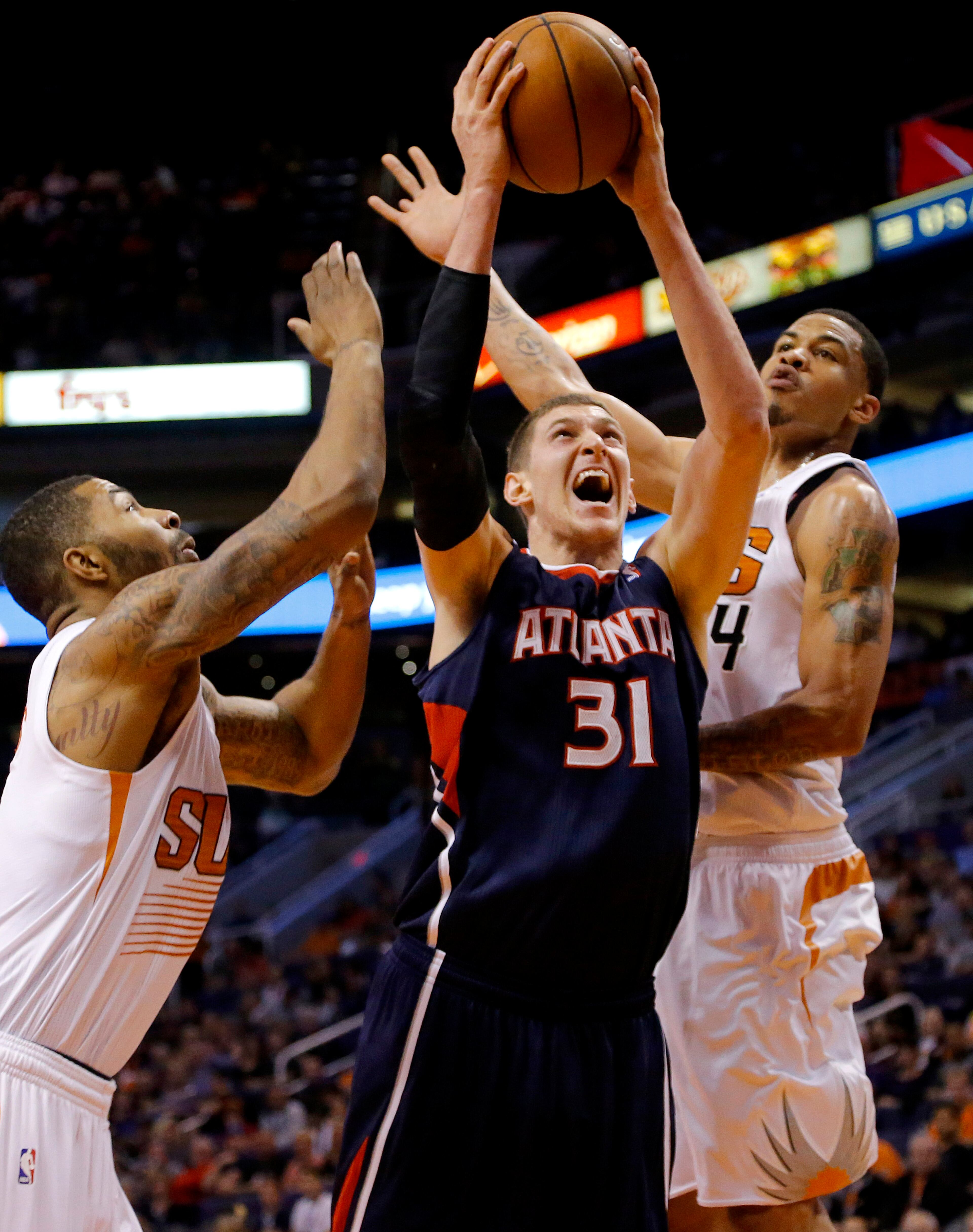 Atlanta Hawks' Mike Muscala (31) drives between Phoenix Suns' Markieff Morris, left, and Gerald Green during the first half of an NBA basketball game, Sunday, March 2, 2014, in Phoenix. (AP Photo/Matt York)