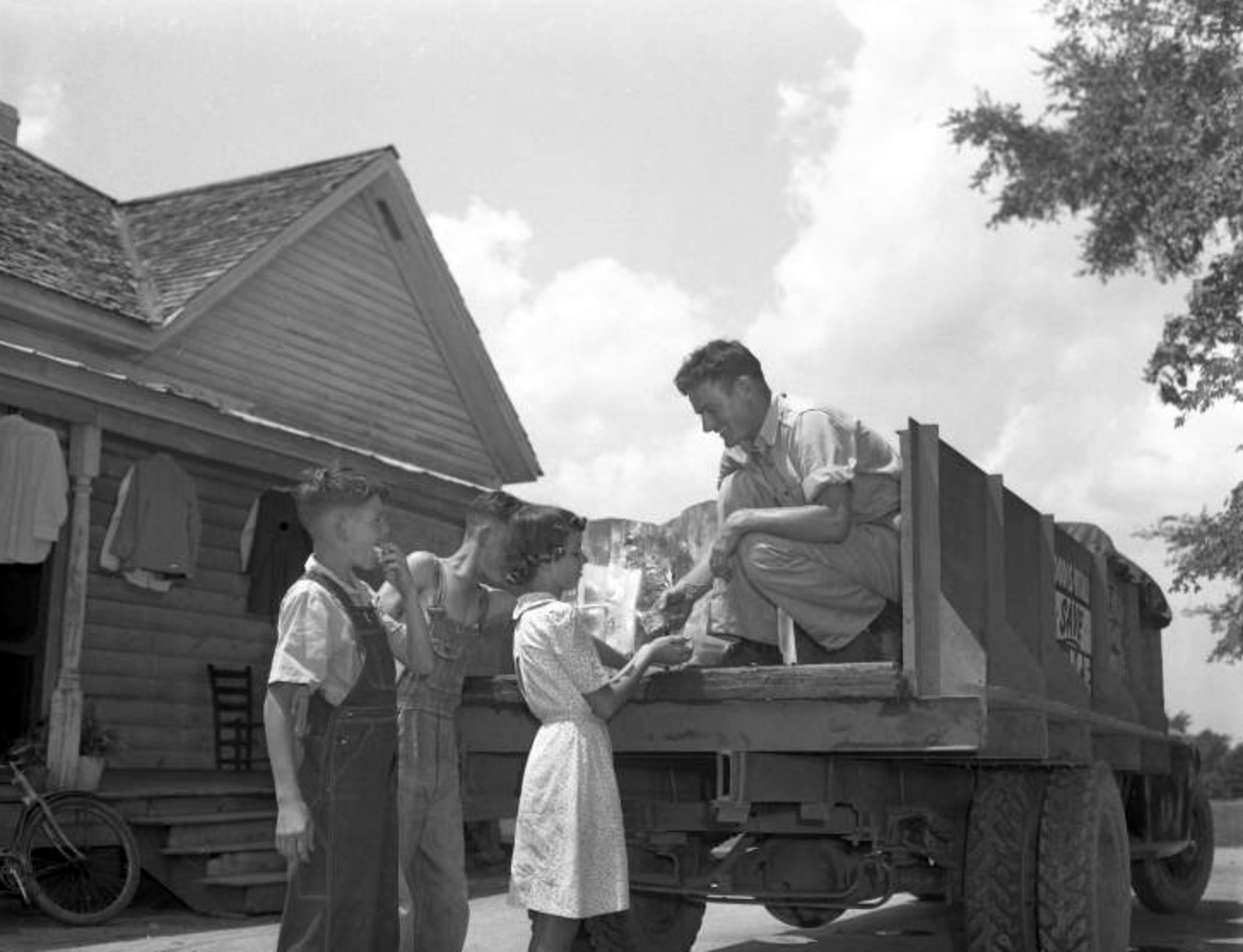 Children are given small pieces of ice from the iceman on a hot day, September1945