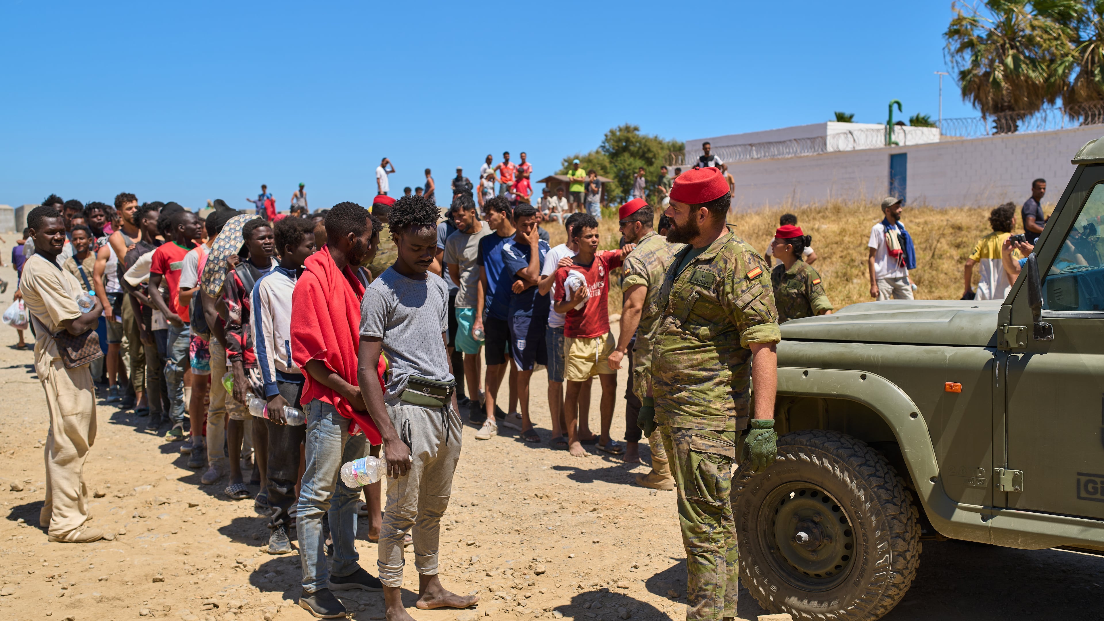 Migrants who crossed into Spain from Morocco line up for water distributed by Spanish soldiers in the Spanish enclave of Ceuta, Sunday, Aug. 2, 2026. (AP Photo/Bernat Armangue)