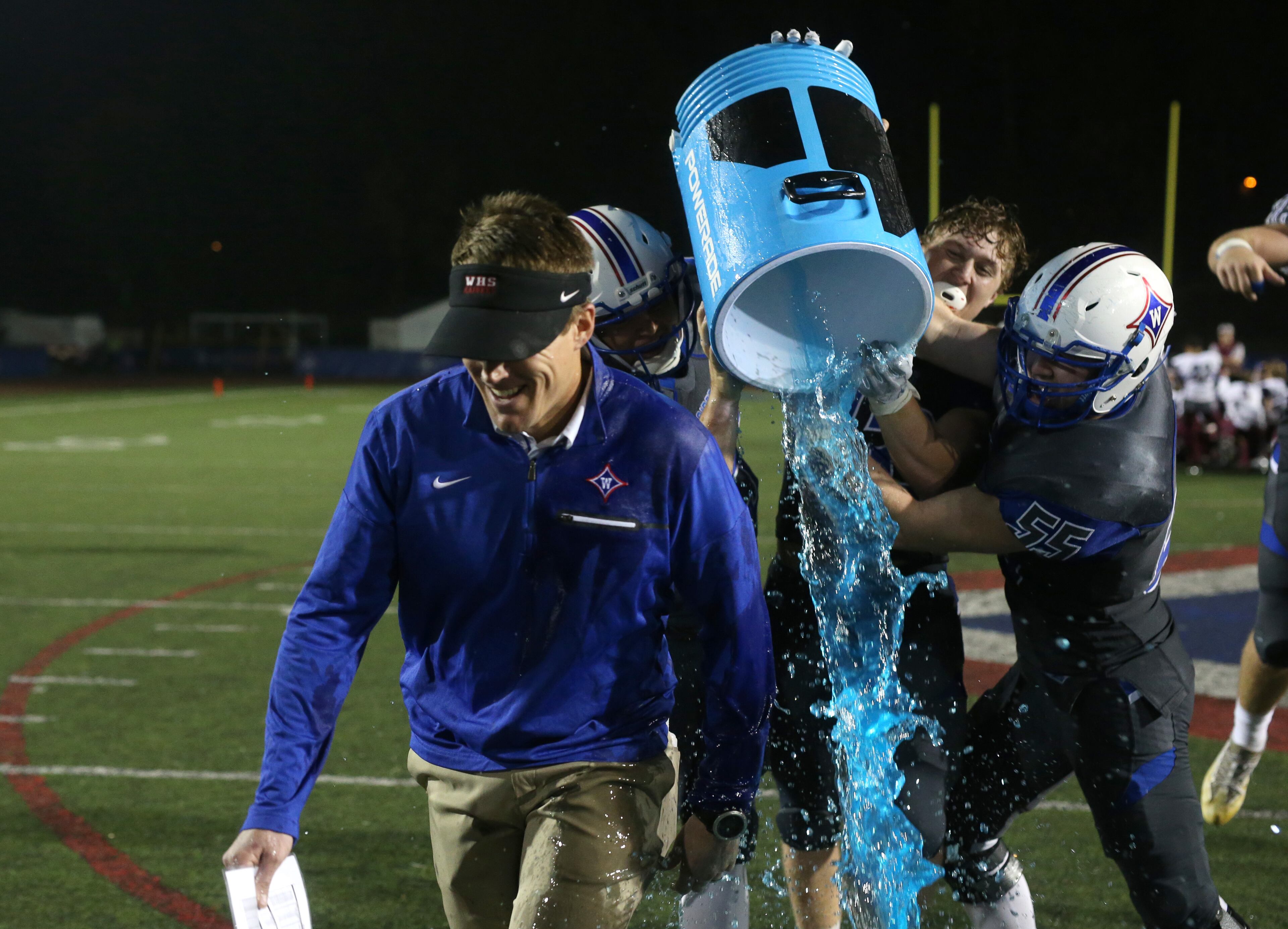 Walton players attempt to give their head coach Daniel Brunner a gatorade dunk as Brunner gives a television interview after their win against Woodstock at Walton High School Friday, November 3, 2017, in Marietta. Walton won 42-37. PHOTO / JASON GETZ