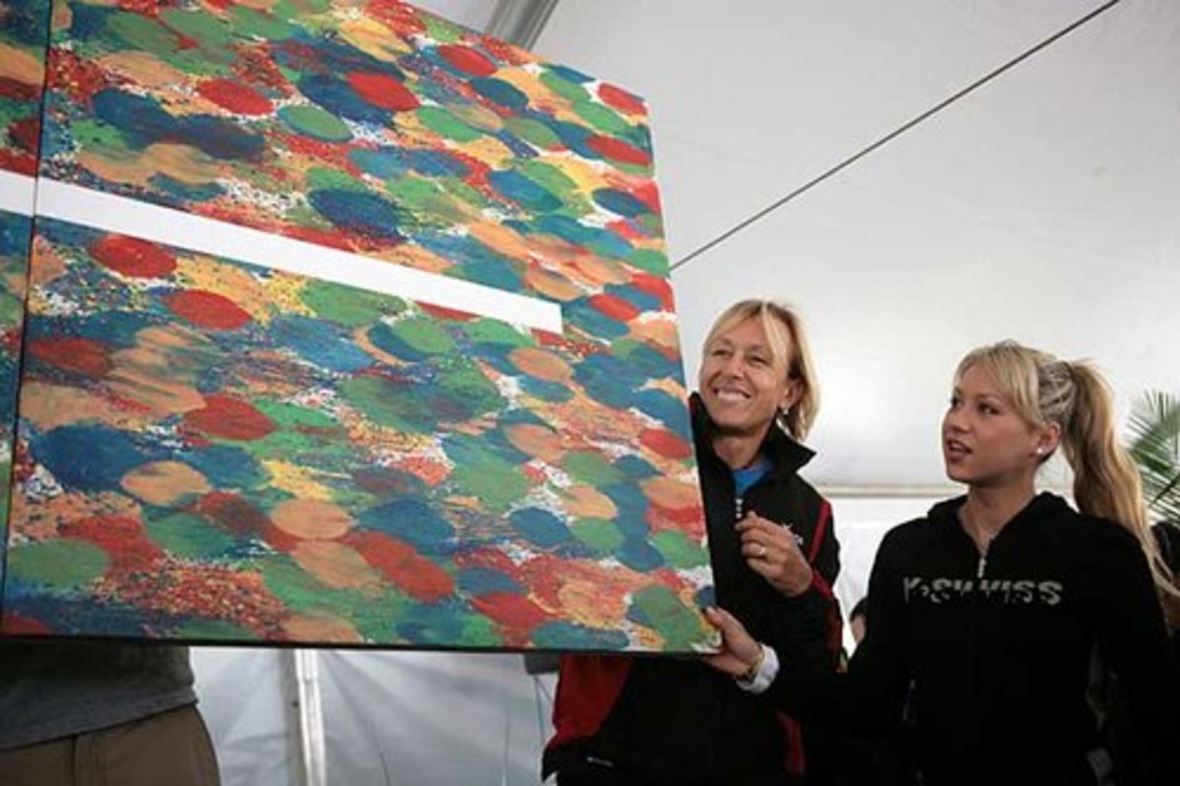 Tennis players Martina Navratilova (left) and Anna Kournikova hold a painting titled "Sweetspots II" created by Navratilova and artist Juraj Kralik at the live auction segment of the Advanta WTT Smash Hits event. The event featured a silent auction, live auction and tennis matches.