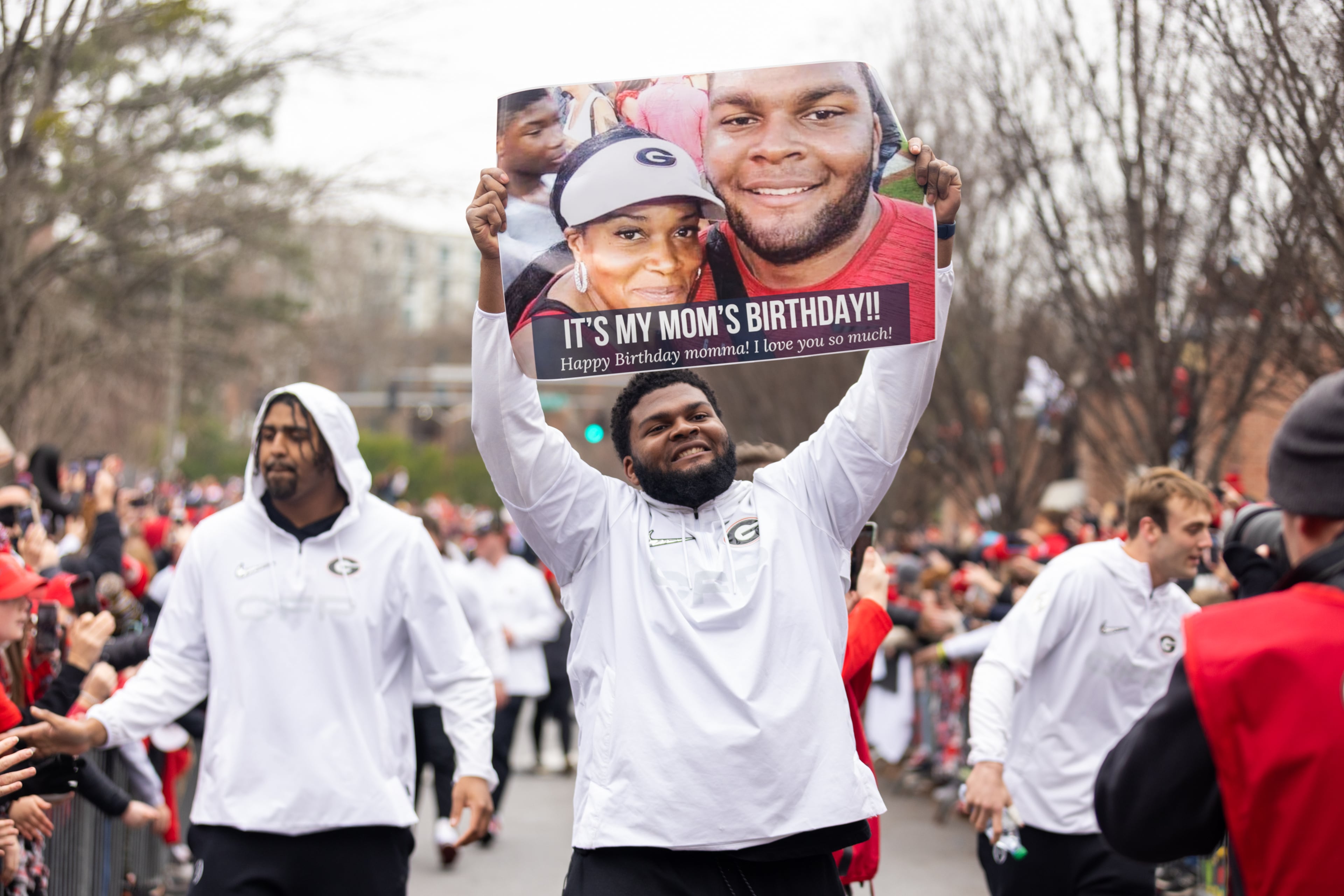University of Georgia football player Jamaree Salyer holds up a sign about his mother’s birthday during the Dawg Walk as part of the team’s celebration parade in Athens, Georgia on January 15th, 2022.(Nathan Posner for The Atlanta Journal-Constitution)