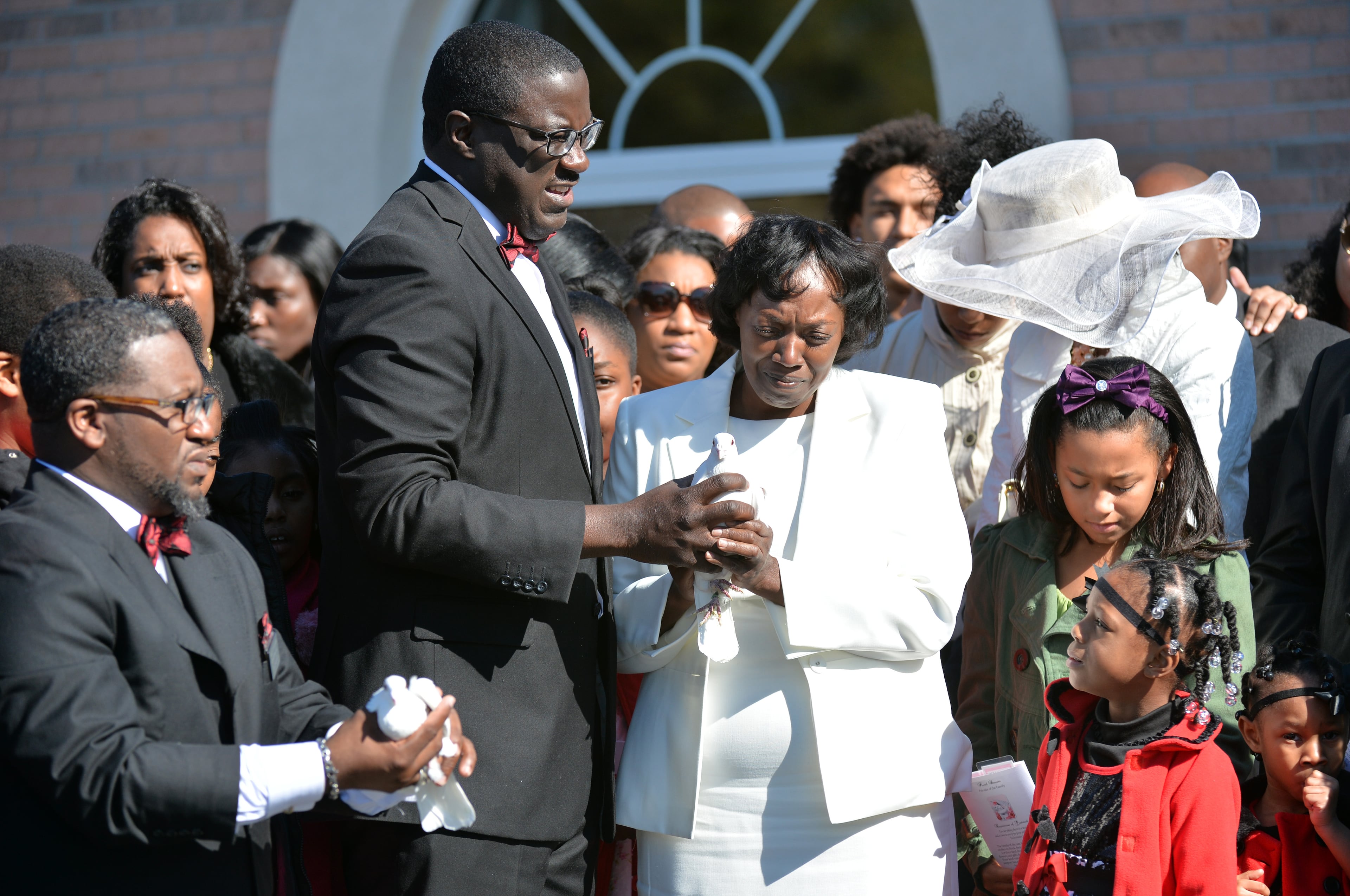 Kevin Evans (center left), director of the funeral home, helps Emani Moss' grandmother Robin Moss (center right) as they prepare to release doves at the funeral service for Emani Moss, who was found dead, her body burned, in a trash can, at Gregory B. Levett & Sons Funeral Home in Lawrenceville on Wednesday, November 13, 2013. Emani Moss will be laid to rest Wednesday in Gwinnett after the grandmother won court approval to bury the child. Emani's grandmother had to get a court order to keep the birth mother, who surrendered custody, from claiming the body. HYOSUB SHIN / HSHIN@AJC.COM