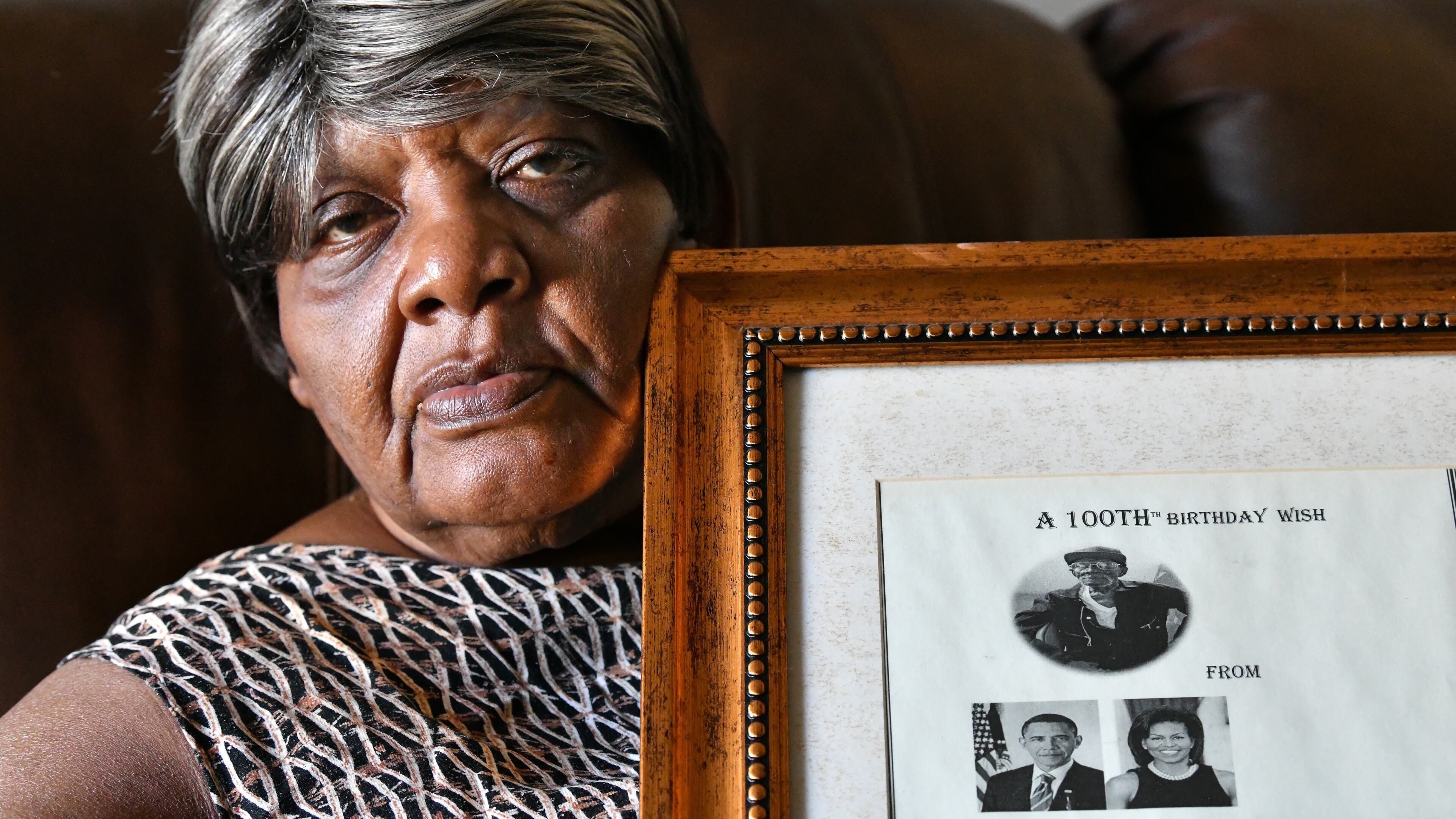 Ruby Jackson holds a framed "100th Birthday Wish" message from Barack and Michelle Obama for her father Charles Coleman, who died of COVID-19 at the age of 106. Coleman, born on July 4, 1914, was a longtime farmer. (Hyosub Shin / Hyosub.Shin@ajc.com)