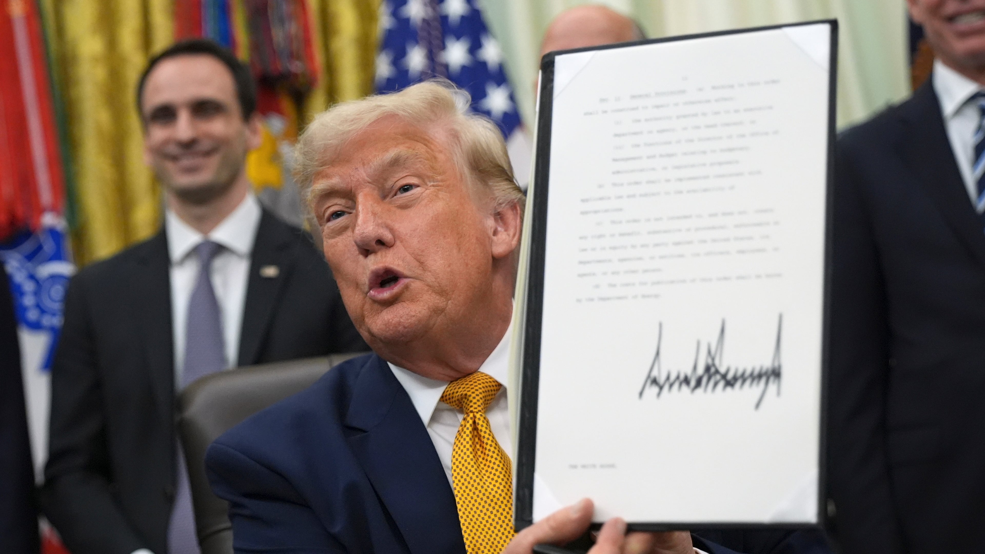 President Donald Trump holds up a signed executive order about quantum computing, in the Oval Office of the White House, Monday, June 22, 2026, in Washington. (AP Photo/Jacquelyn Martin)
