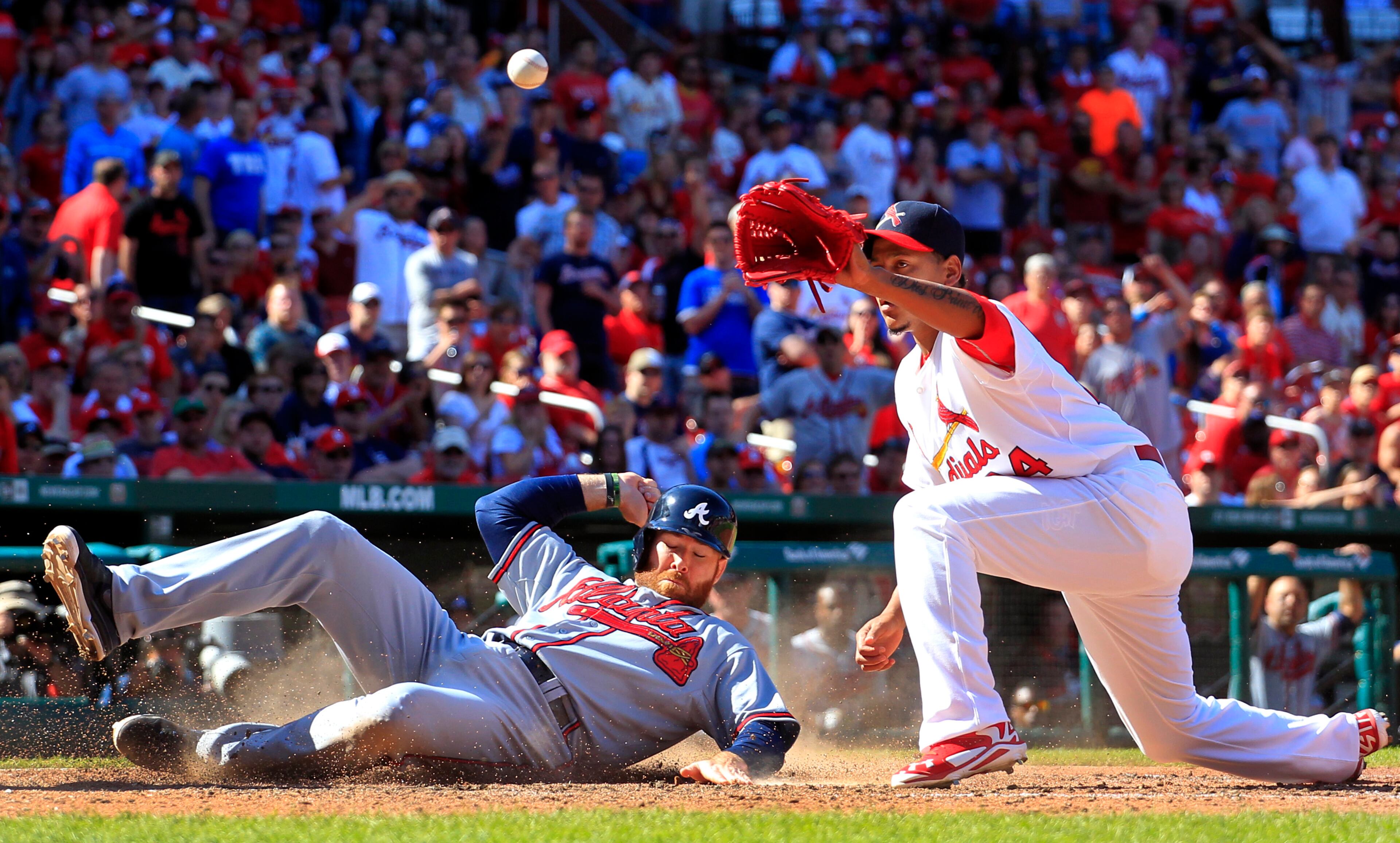 Atlanta Braves' Ryan Doumit, left, scores on a wild pitch by St. Louis Cardinals relief pitcher Carlos Martinez, right, as Martinez covers home during the ninth inning of a baseball game Sunday, May 18, 2014, in St. Louis. (AP Photo/Jeff Roberson)