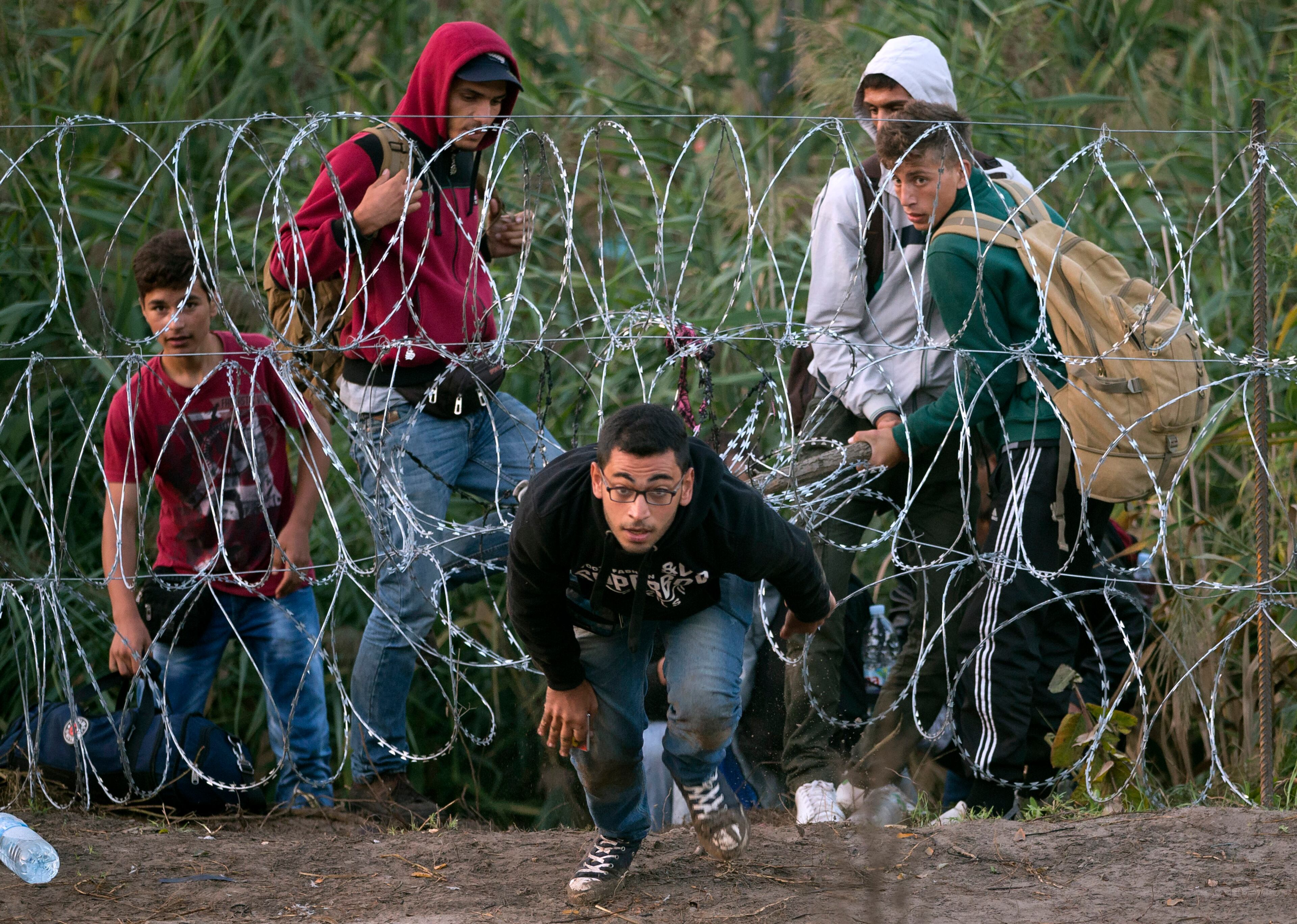A Syrian refugee runs after entering Hungary from Serbia through a barbed wire fence, on the border near Roszke, Friday, Aug. 28, 2015. Hungary deployed police reinforcements to rein in an unrelenting flow of migrants across its porous border Thursday, but refugee activists said the effort appeared futile in a nation whose migrant camps are overloaded and barely delay their journeys west into the heart of the European Union.
