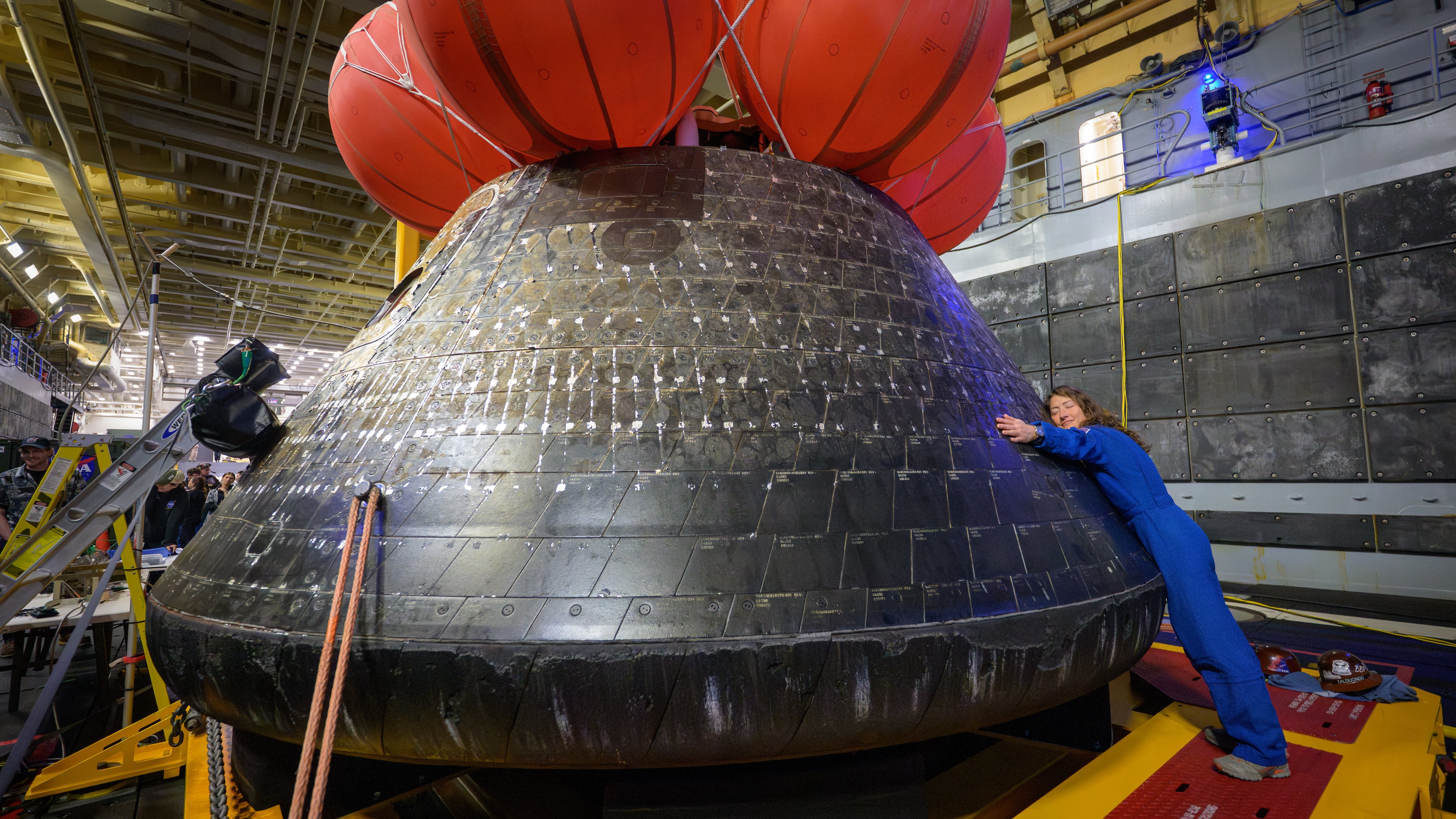 In this photo provided by NASA, Artemis II mission specialist and NASA astronaut Christina Koch hugs the Orion spacecraft aboard the USS John P. Murtha, Saturday, April 11, 2026, off the coast of California. (Bill Ingalls/NASA via AP)