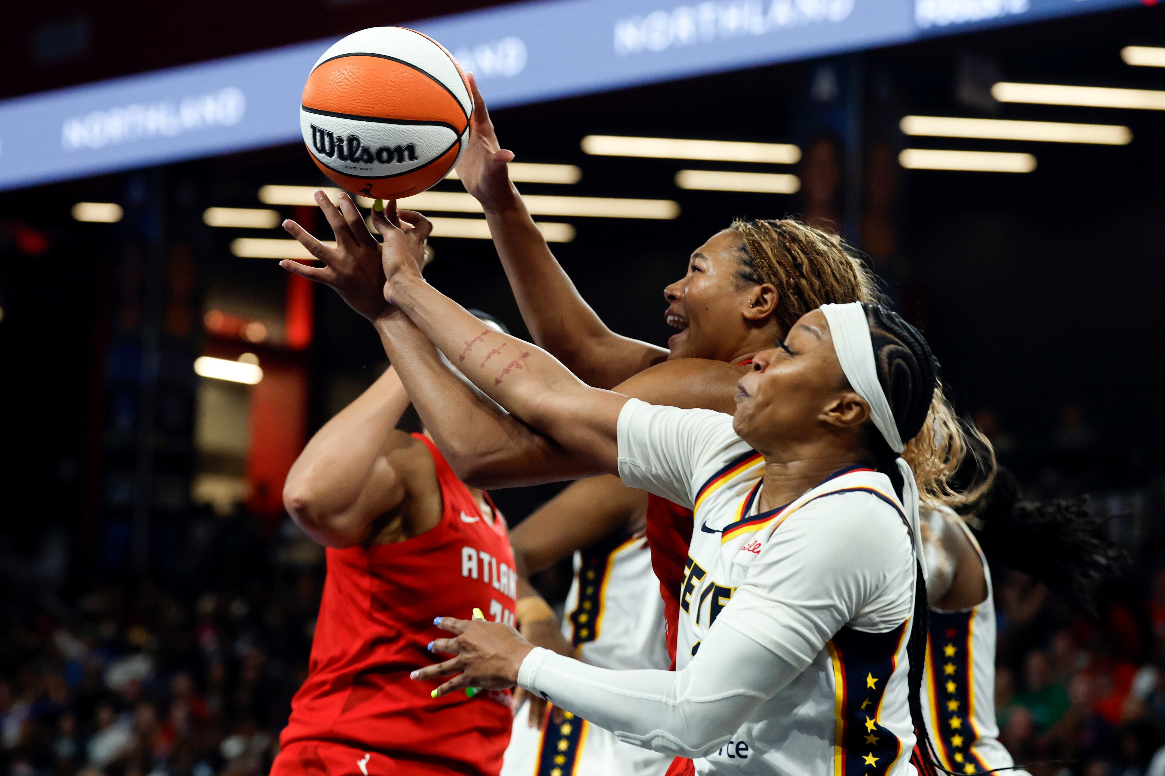 Indiana Fever guard Odyssey Sims, front right, and Atlanta Dream forward Naz Hillman, left, battle for a rebound during the second half of Game 3 in the first round of the WNBA basketball playoffs, Thursday, Sept. 18, 2025, in Atlanta. (AP Photo/Butch Dill)
