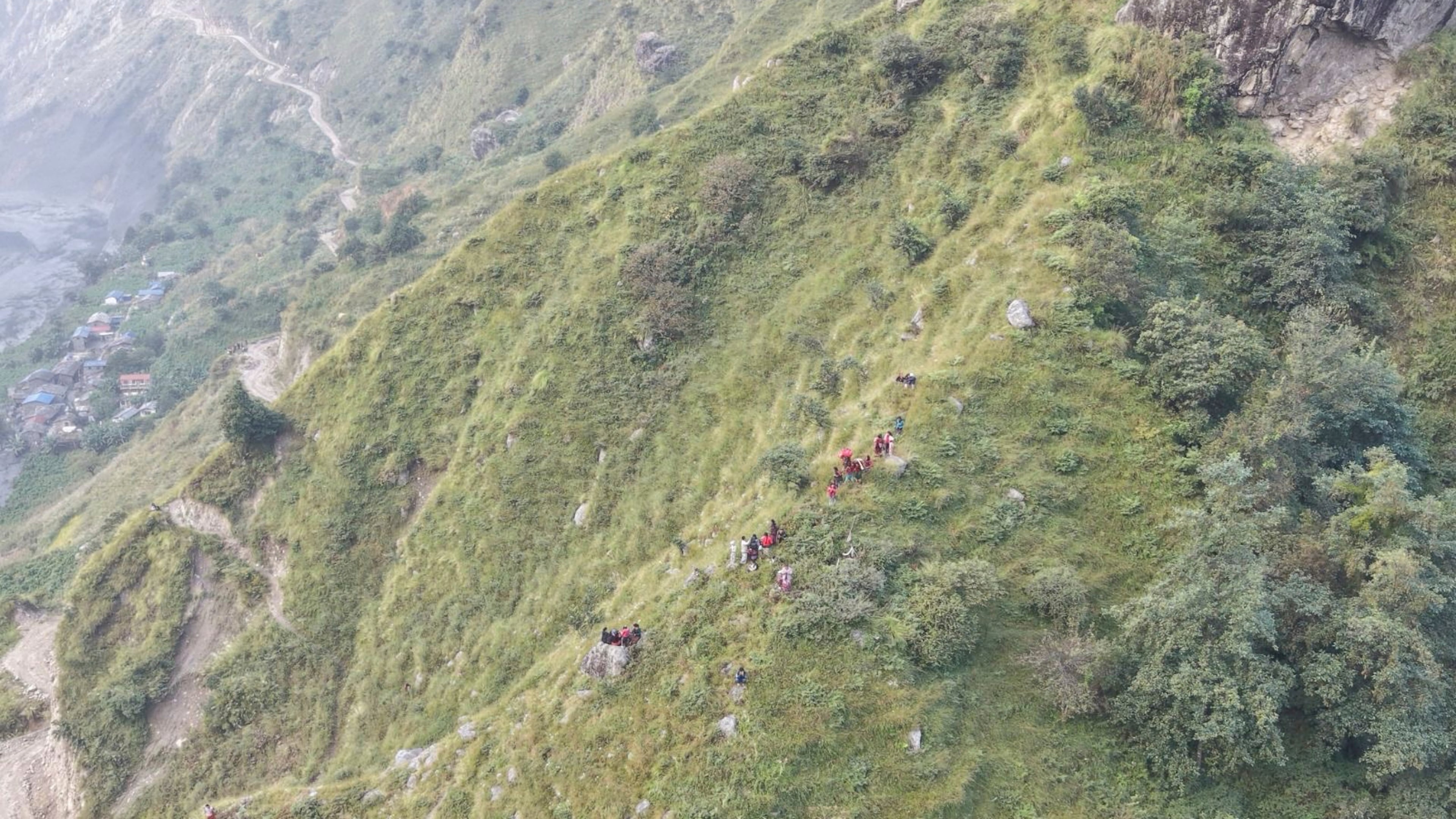 In this photo provided by the National Trust for Nature Conservation-Manaslu Conservation Area Project (NTNC-MCAP), survivors sit on higher ground in Gorkha district after flooding in the Budhi Gandaki River in north central Nepal, Sunday, Oct. 11, 2026. (NTNC-MCAP via AP)