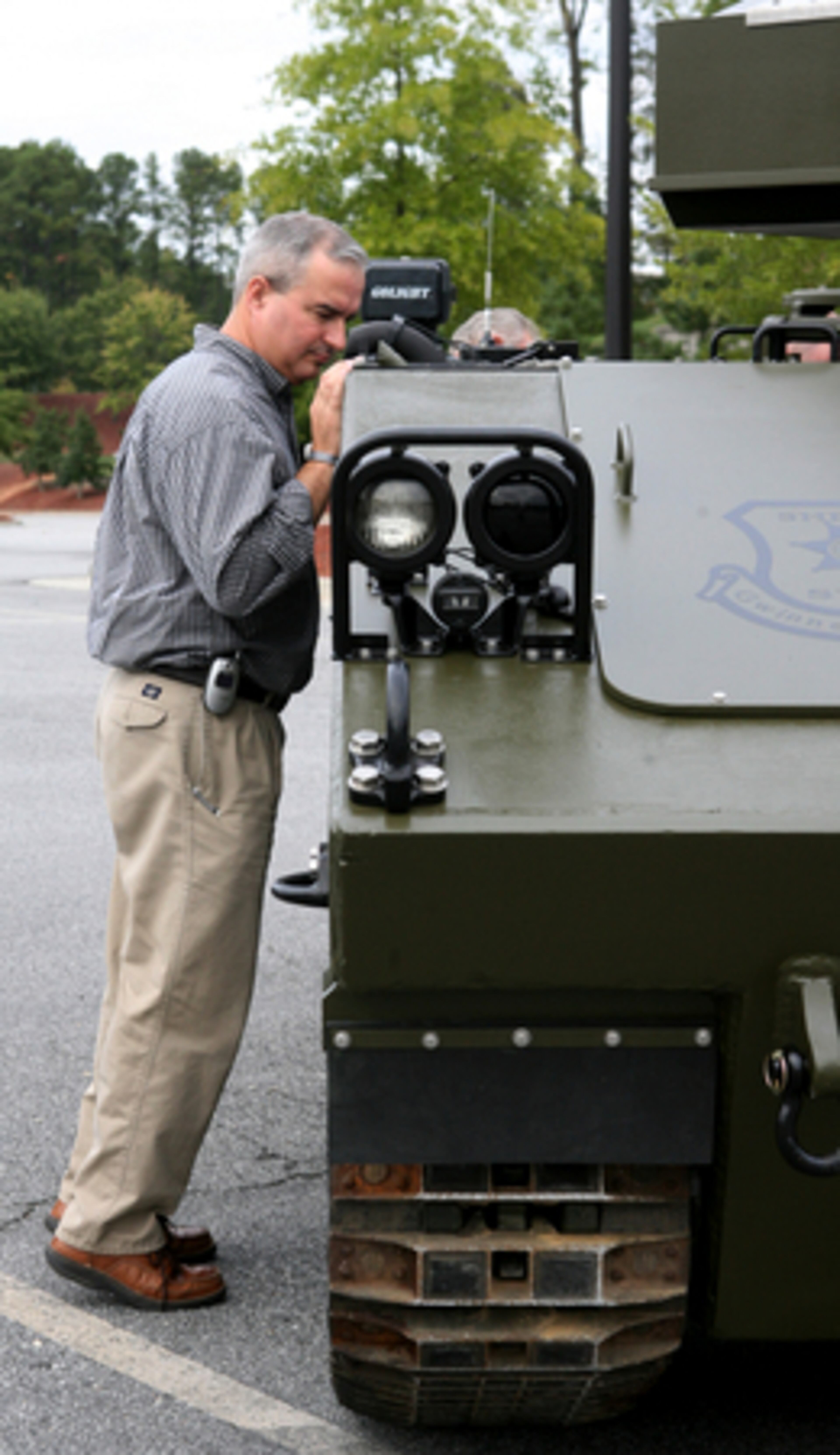 Michael Kulp, of Snellville, gets on his toes to peer at an M-114 armored personnel carrier owned by the Gwinnett County Sheriff's SWAT team at one of the parking lot displays. The Festival helps encourage postive interaction between the public and law officers. The carrier can hold three officers and one driver.
