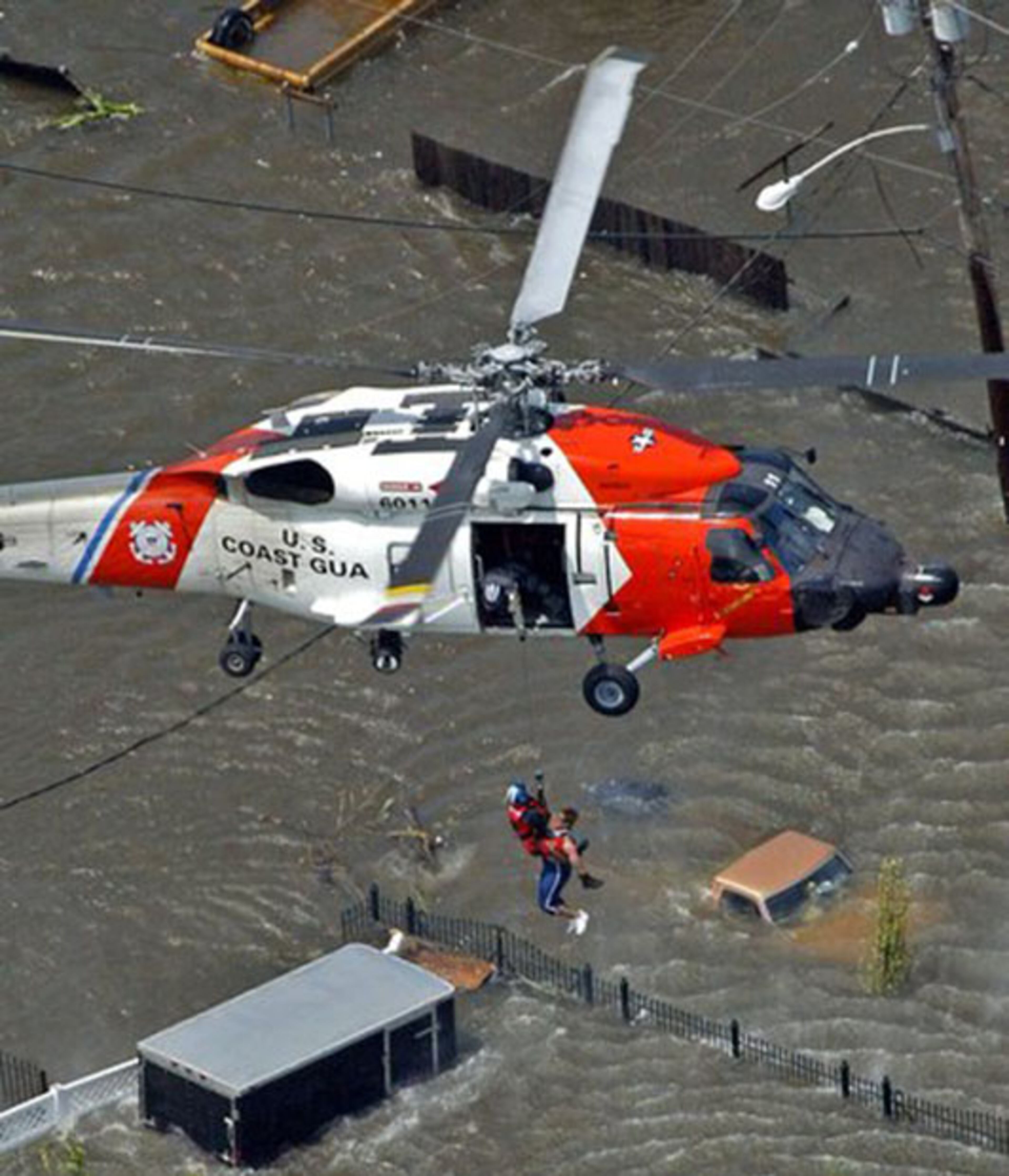 A New Orleans resident is rescued from the rooftop of a home by a U.S. Coast Guard helicopter crew as floodwaters from Hurricane Katrina cover the streets.