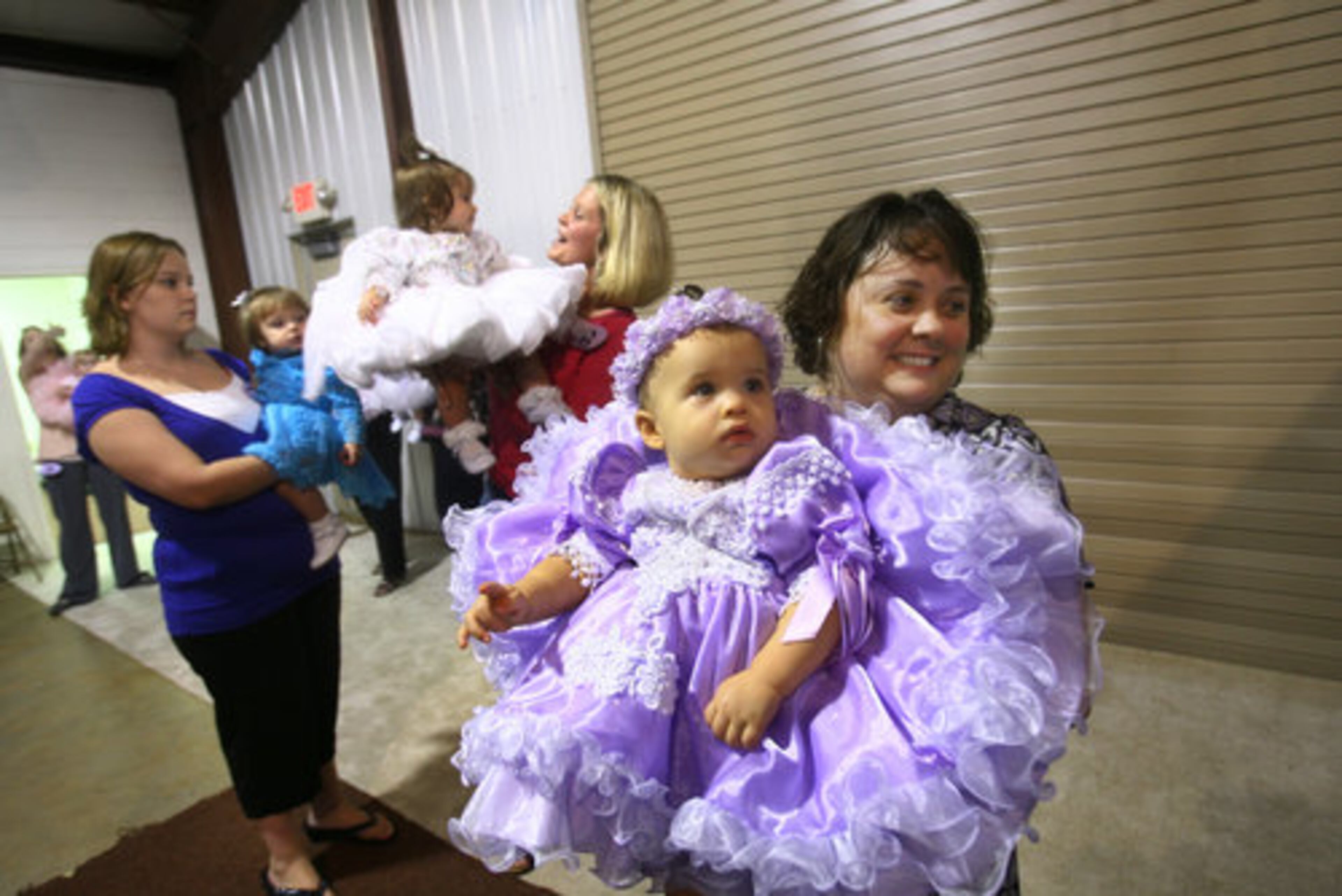 Katie Westmoreland, 11 months, (purple dress) and her mom, Tonya Westmoreland, wait backstage. In background, Jessica Moon holds daughter Madilyn (blue dress) while Wendy Dickey lifts her daughter Paisley Scott Dickey (white dress).