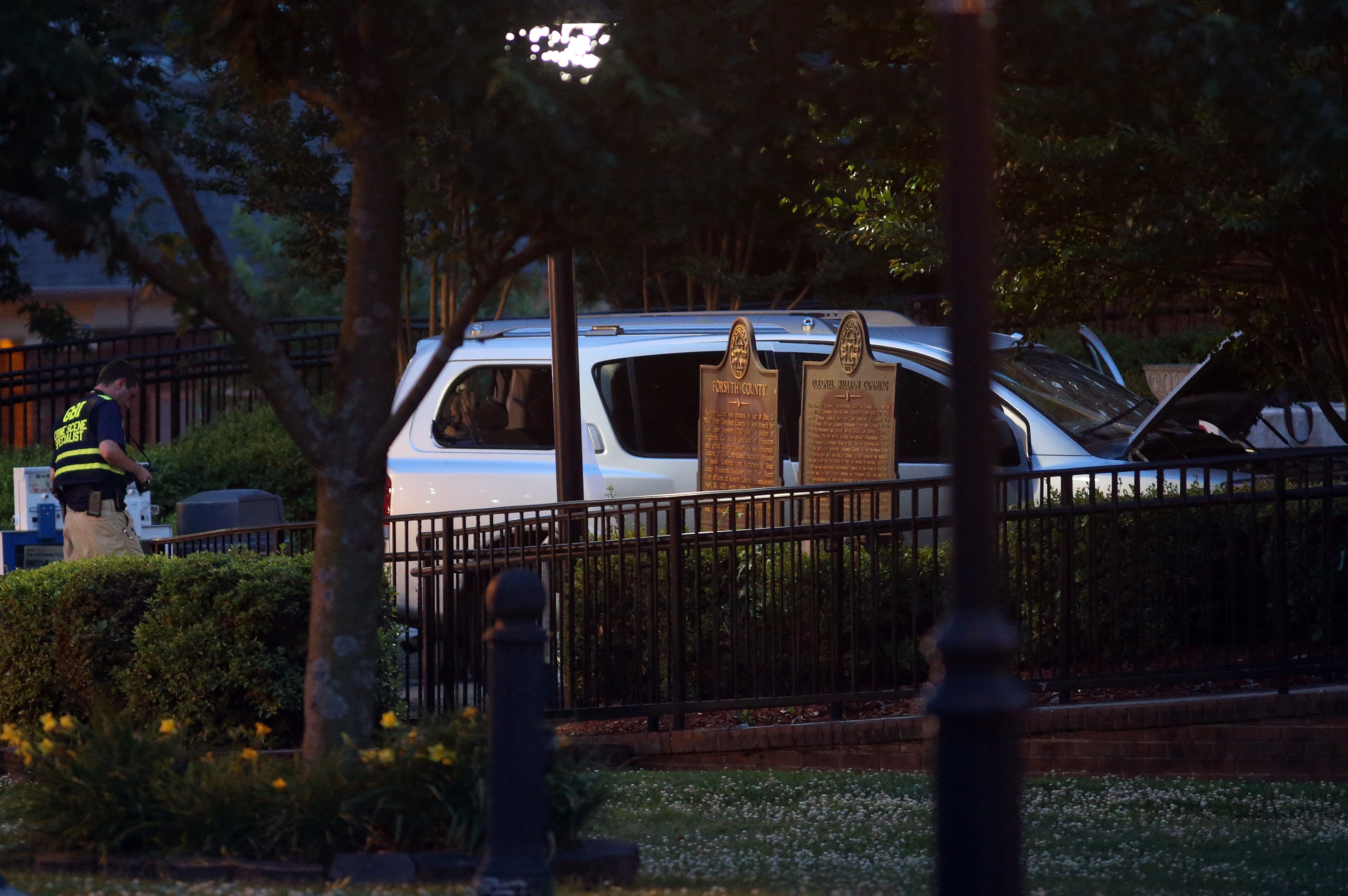 A GBI agent passes by the Nissan Armada Friday evening June 6, 2014 used by accused Forsyth County Courthouse shooter Dennis Marx earlier that morning. The shoot out left one deputy injured and the perpetrator dead.