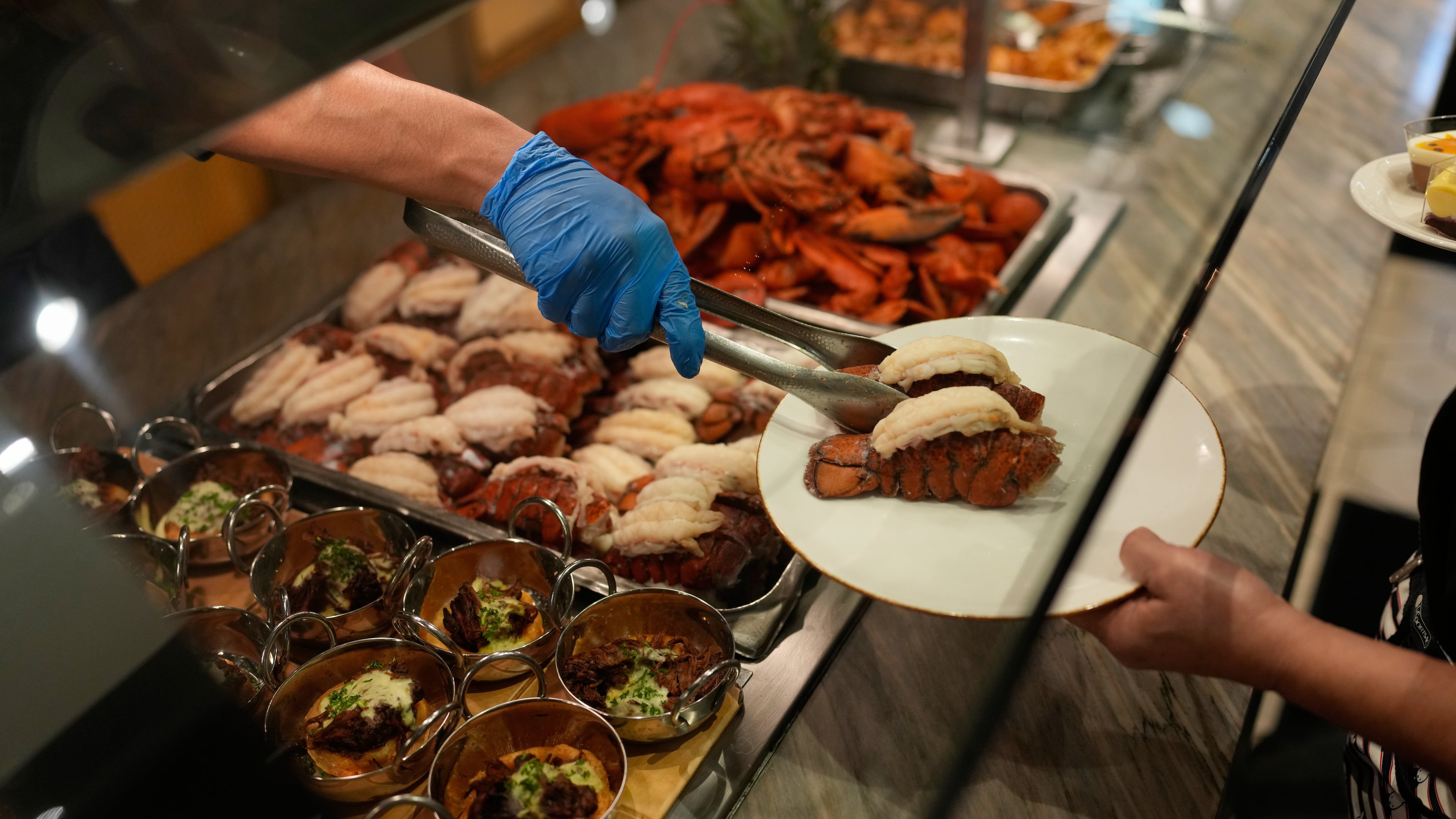 A person serves lobster tails at the A.Y.C.E Buffet in the Palms resort-casino Wednesday, Jan. 28, 2026, in Las Vegas. (AP Photo/John Locher)