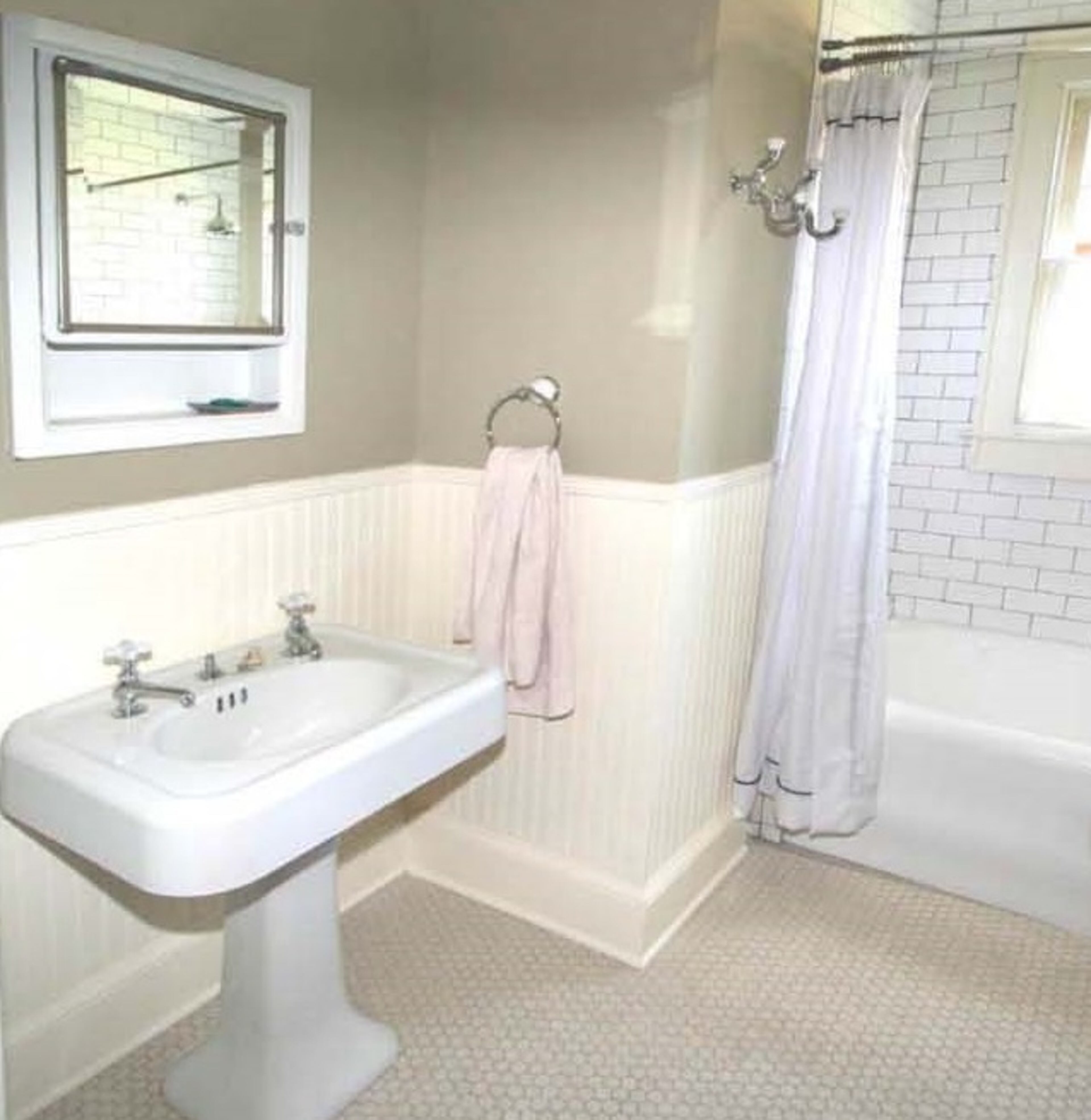 The powder room is now freshened up with white subway tile, hexagon tile flooring and beadboard wainscoting.