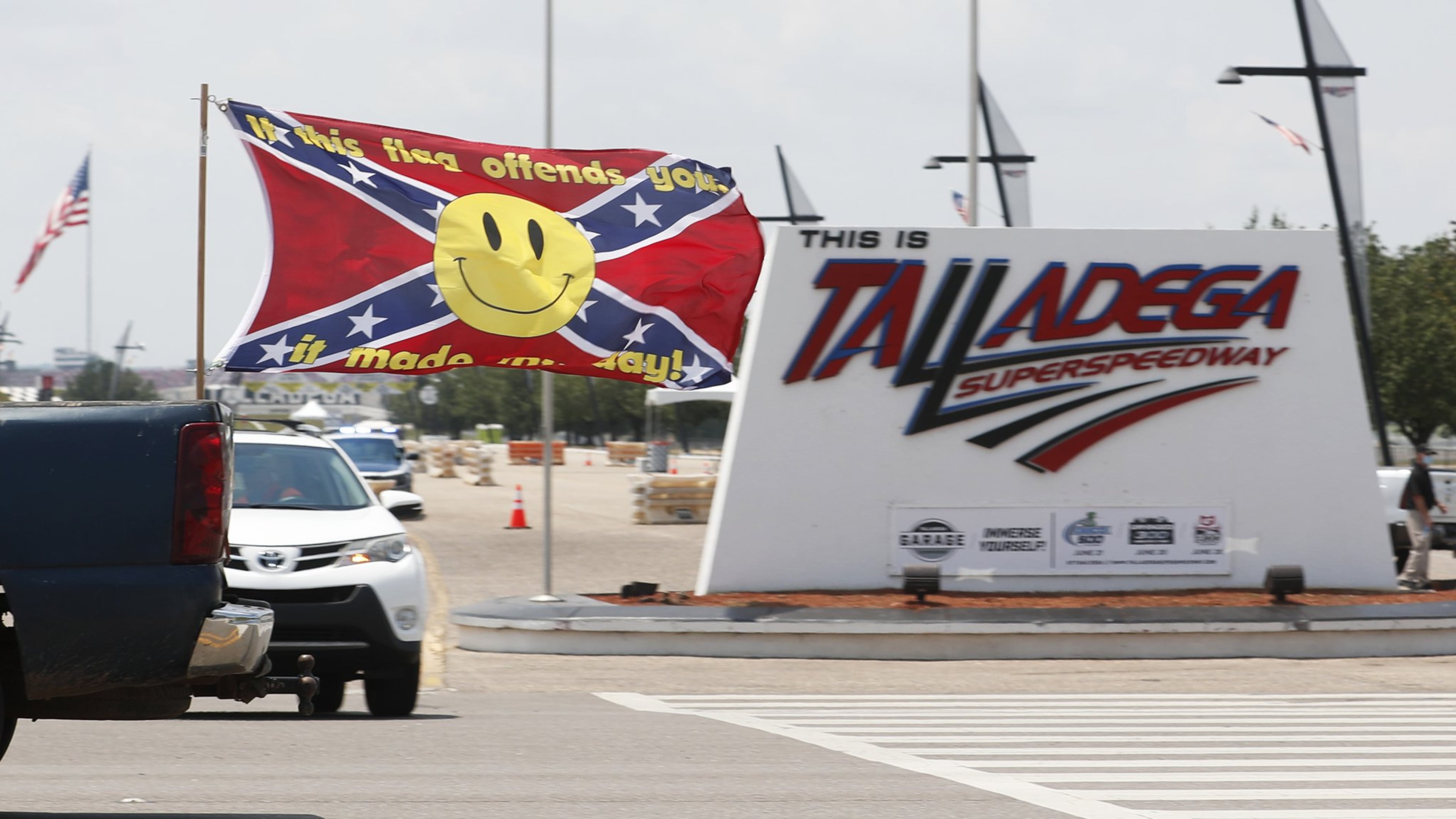 Race fans fly Confederate battle flags and United States flags as they drive by the entrance to Talladega Superspeedway prior to a NASCAR Cup Series auto race in Talladega Ala., Sunday, June 21, 2020.. (AP Photo/John Bazemore)