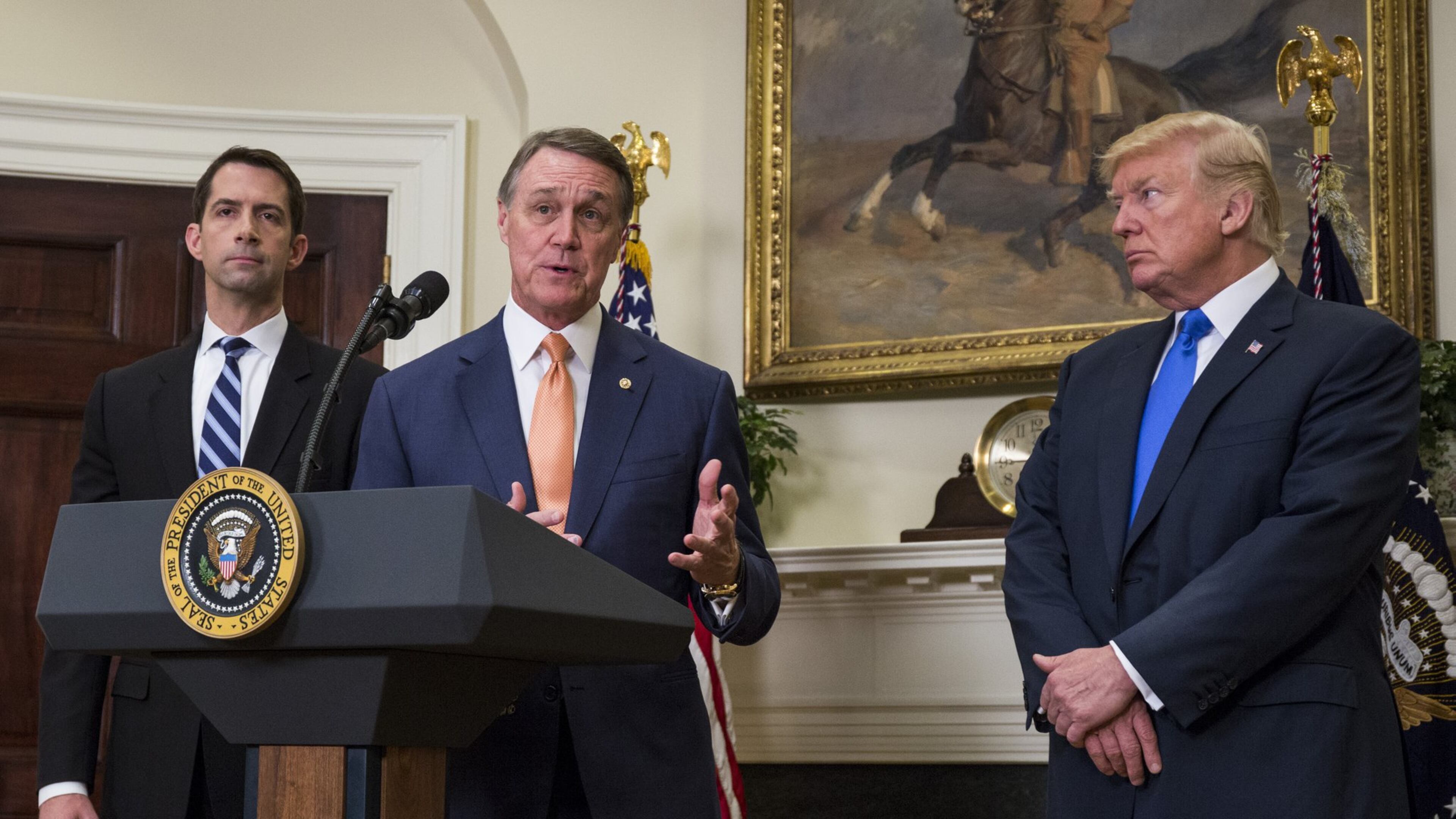 U.S. Sen. David Perdue, R-Ga., makes an announcement in August on the introduction of the Reforming American Immigration for a Strong Economy (RAISE) Act in the Roosevelt Room at the White House. The act aims to overhaul U.S. immigration by moving toward a “merit-based” system. Also pictured are U.S. Sen. Tom Cotton, R-Ark., left, and President Donald Trump. (Photo by Zach Gibson Pool/Getty Images)