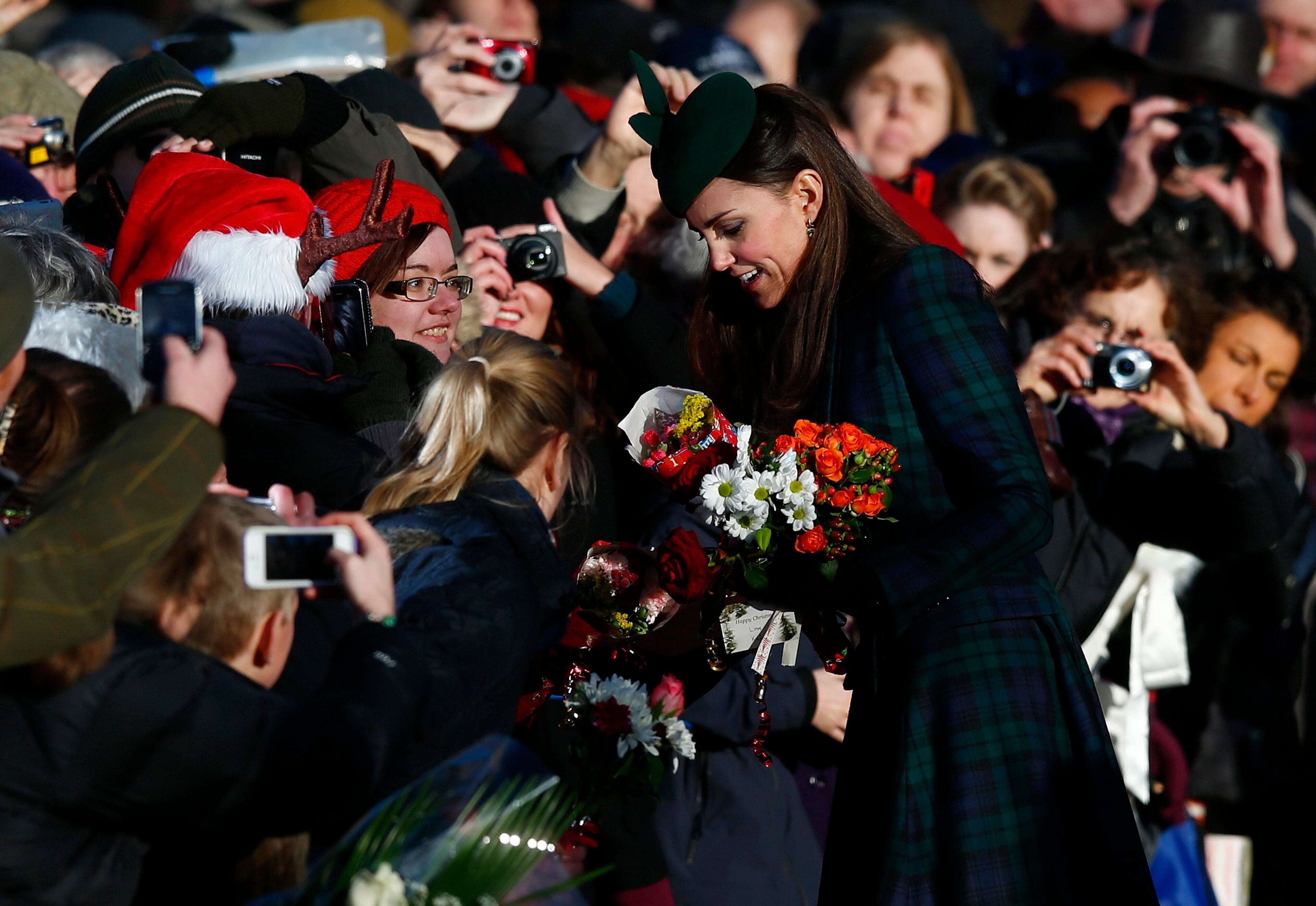 Britain's Catherine, the Duchess of Cambridge, receives flowers from well-wishers as she leaves a Christmas Day morning service at the church on the Sandringham Estate in Norfolk, eastern England, December 25, 2013. REUTERS/Andrew Winning