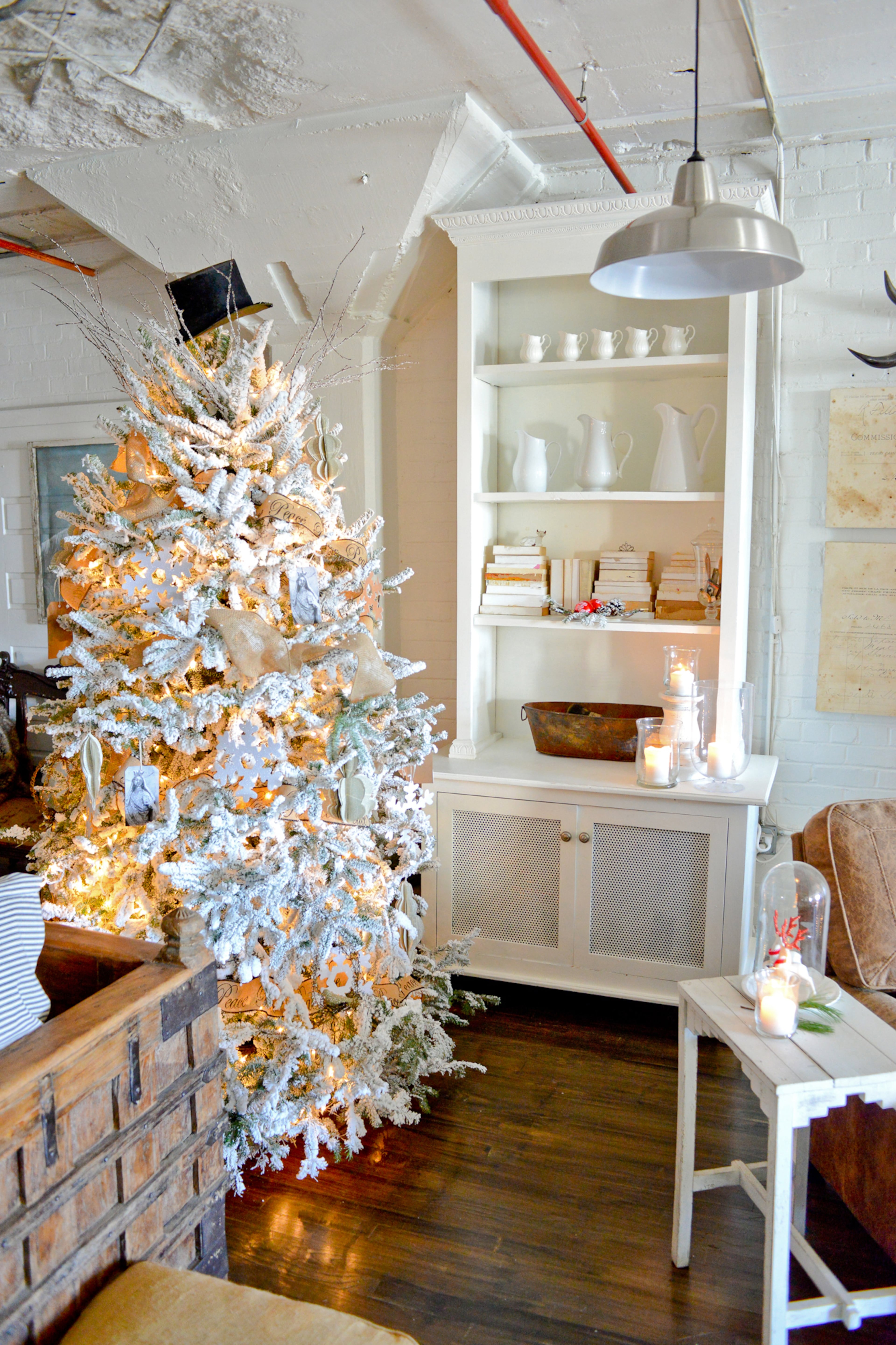 A top hat is a quirky touch on the Christmas tree in Kelli and Lloyd Hawk's Atlanta loft. The white bookshelf and dinnerware on display seem to blend into the painted brick walls.