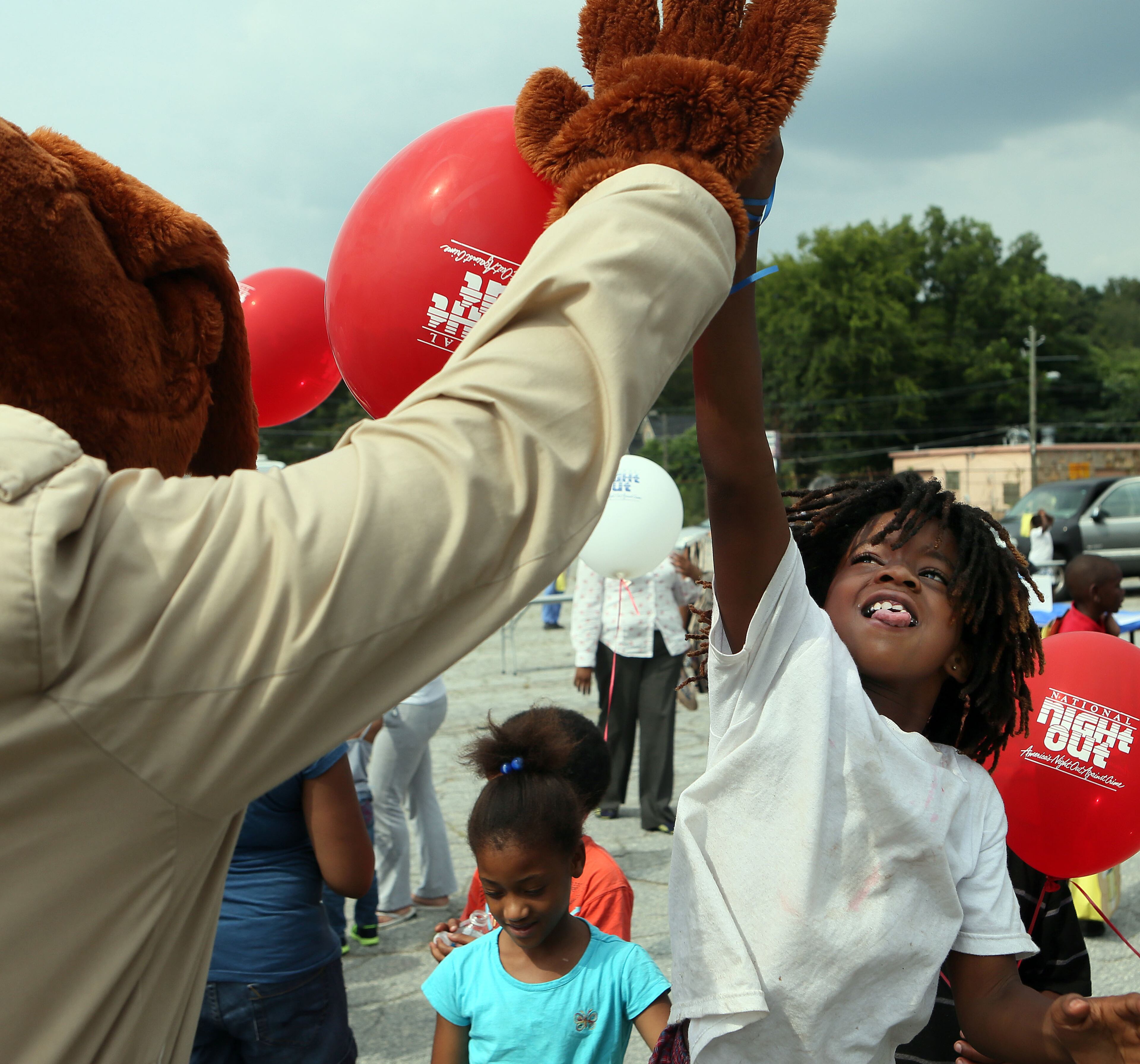 Marquez Broner (age 8) jumped up to high five Officer McGruff during the 30th anniversary of National Night Out in the Pittsburg area of Atlanta on Tuesday.