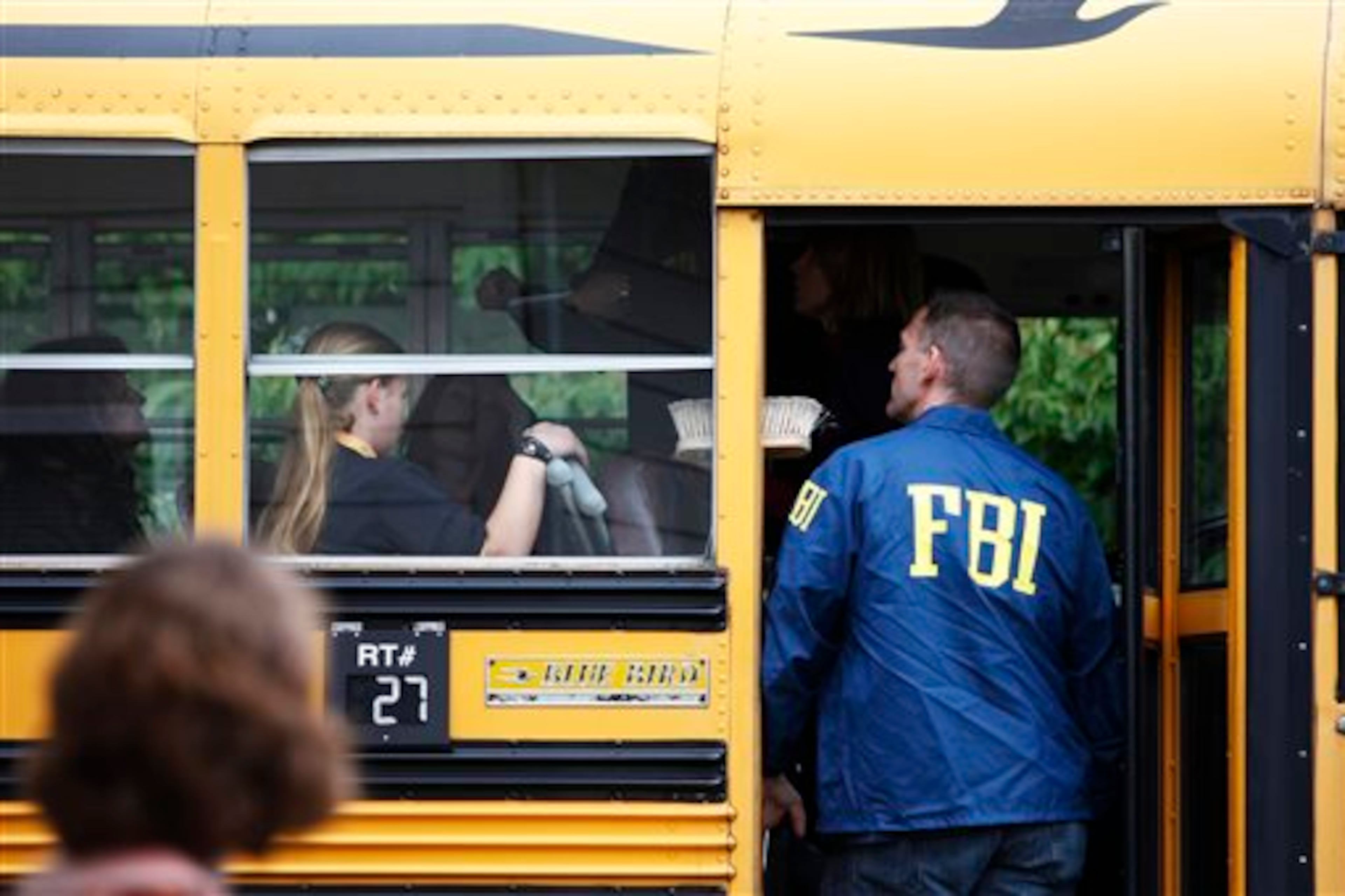 An FBI agent speaks to students on a bus outside of Shoultes Christian Assembly just northwest of Marysville Pilchuck High School in Marysville Friday, Oct. 24, 2014 Students were evacuated by bus to the location after a shooting at the school Friday morning. A student walked into his Seattle-area high school cafeteria on Friday and without shouting or arguing, opened fire, killing one person and shooting several others in the head before turning the gun on himself, officials and witnesses said. (AP Photo/The Herald, Genna Martin)