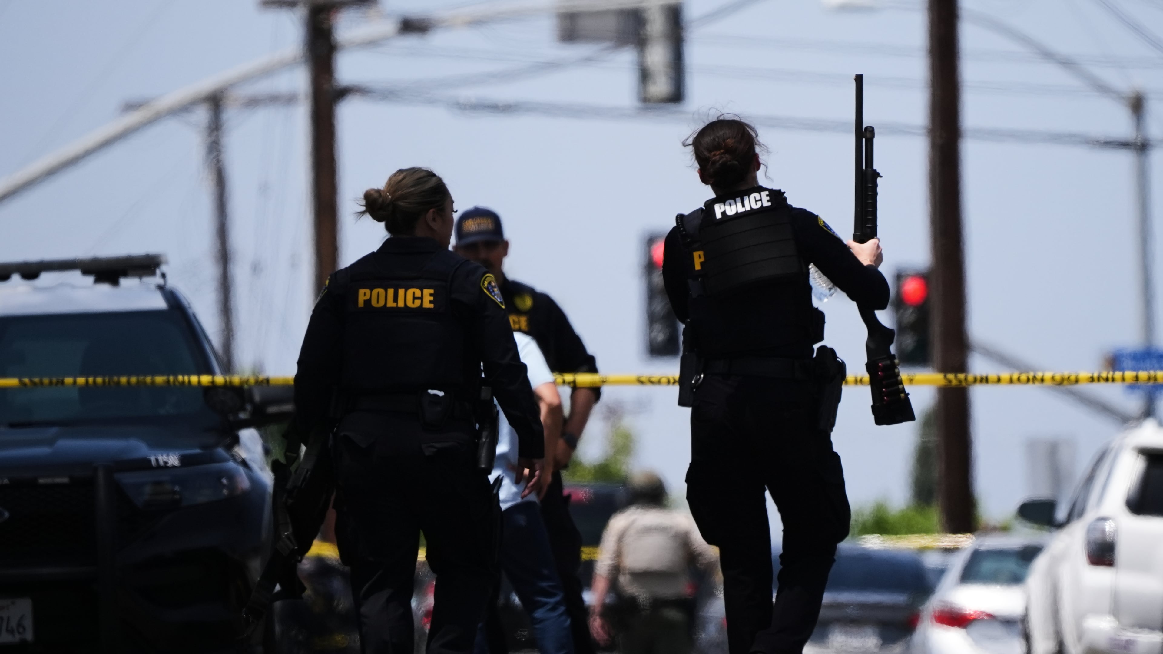 People carry weapons at the scene of a shooting outside the Islamic Center of San Diego Monday, May 18, 2026, in San Diego. (AP Photo/Gregory Bull)