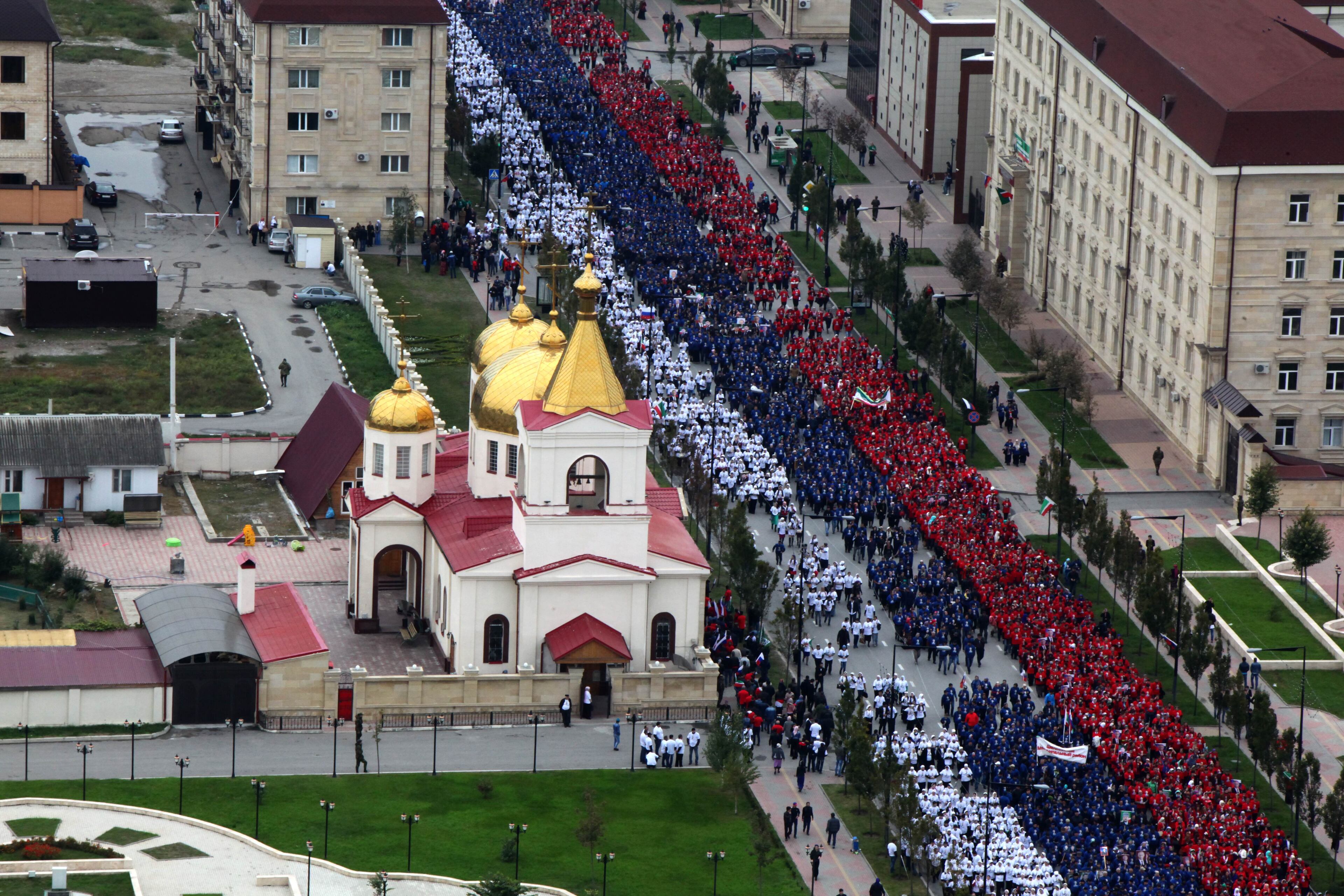 People dressed in colors of Russian flag march in Grozny, Russia, Tuesday, Oct. 7, 2014. In the Chechen capital of Grozny, thousands gathered to form a 600-meter long Russian flag through the streets. Russian President Vladimir Putin is celebrating his 62nd birthday in the wilderness of Siberia, as supporters from across Russia create tributes in his honor. (AP Photo/ Musa Sadulayev)