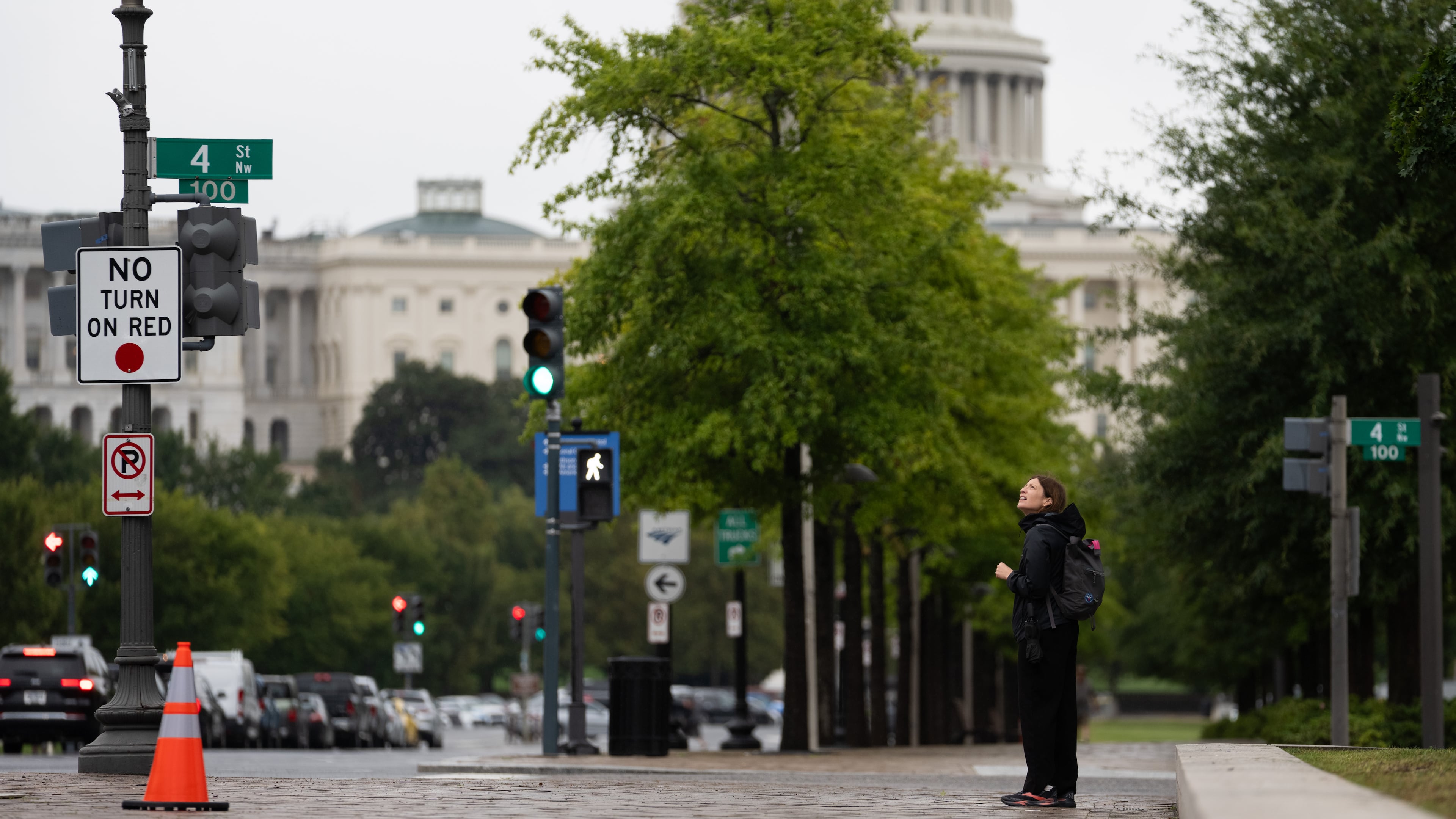 An individual watches a protester scale a light pole and unfurl a banner to protest the upcoming State Visit by China's President Xi Jinping, Tuesday, Sept. 22, 2026, in Washington. (AP Photo/Allison Robbert)