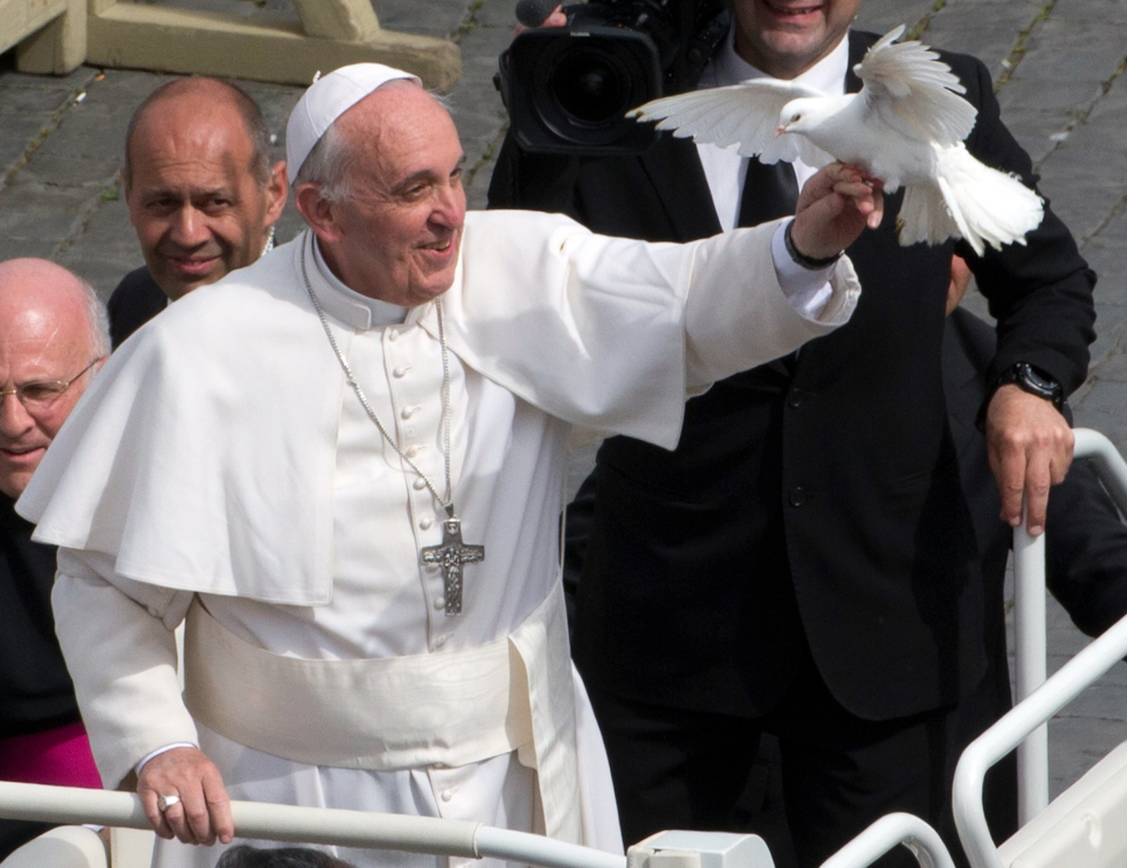 Pope Francis frees a dove during his weekly general audience in St. Peter Square at the Vatican, Wednesday, May 15, 2013. As Francis toured the square in his open-topped popemobile at his Wednesday audience with the public, someone at the edge of the crowd thrust a white bird cage at him. Looking puzzled, his security detail took the cage, containing a pair of white doves, and handed it to Francis. Without hesitation, the pope opened the cage door, thrust a hand inside and extracted one dove, and with a flick of his hand, sent the bird flying over the square. (AP Photo/Alessandra Tarantino)