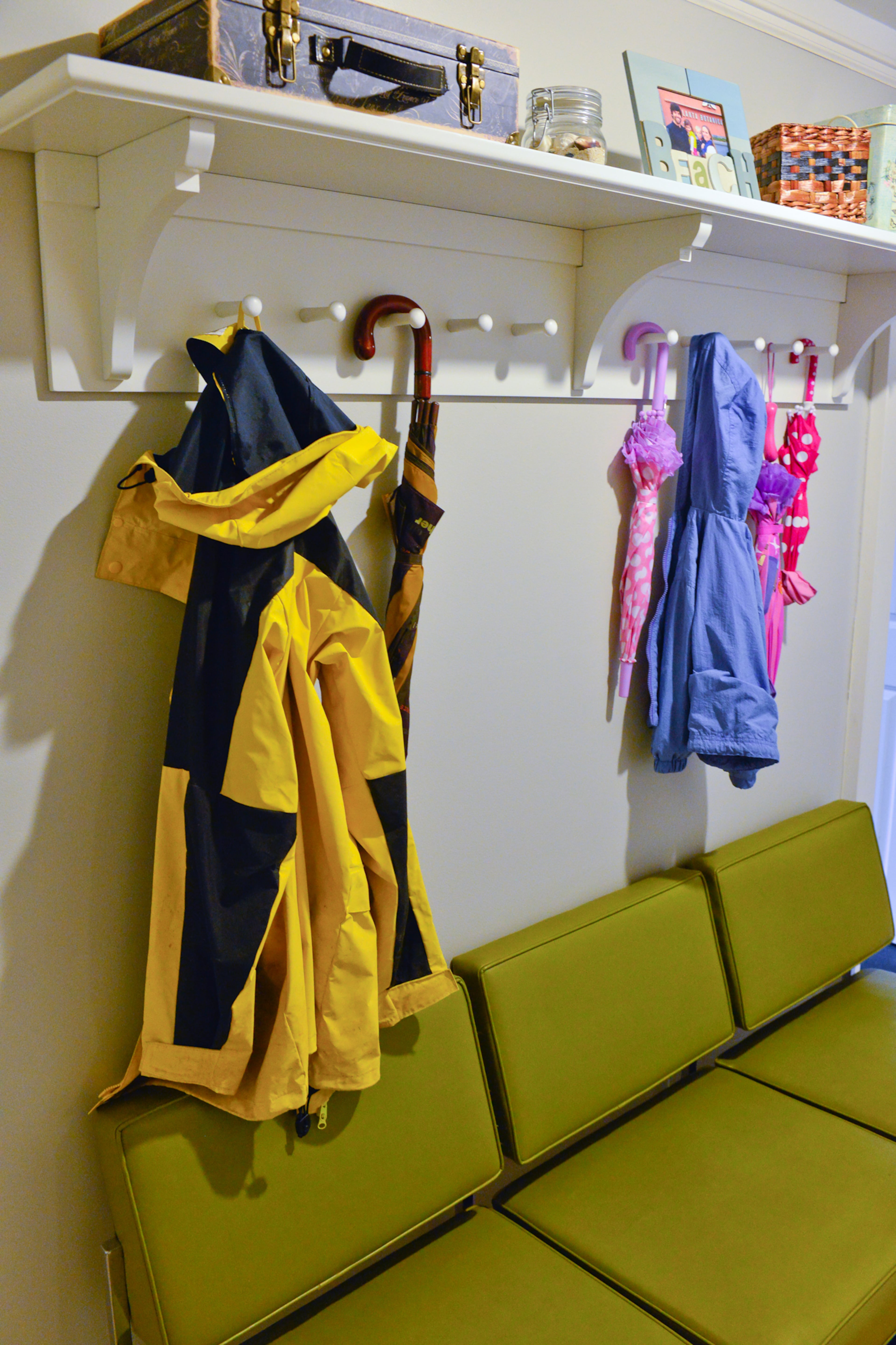 The mudroom just off the garage includes a long row of pegs to keep the family's coats and umbrellas organized. A green couch from Kudzu Antiques provides a stylish place for Alyssa and Peter Olson's children to get ready for the day.