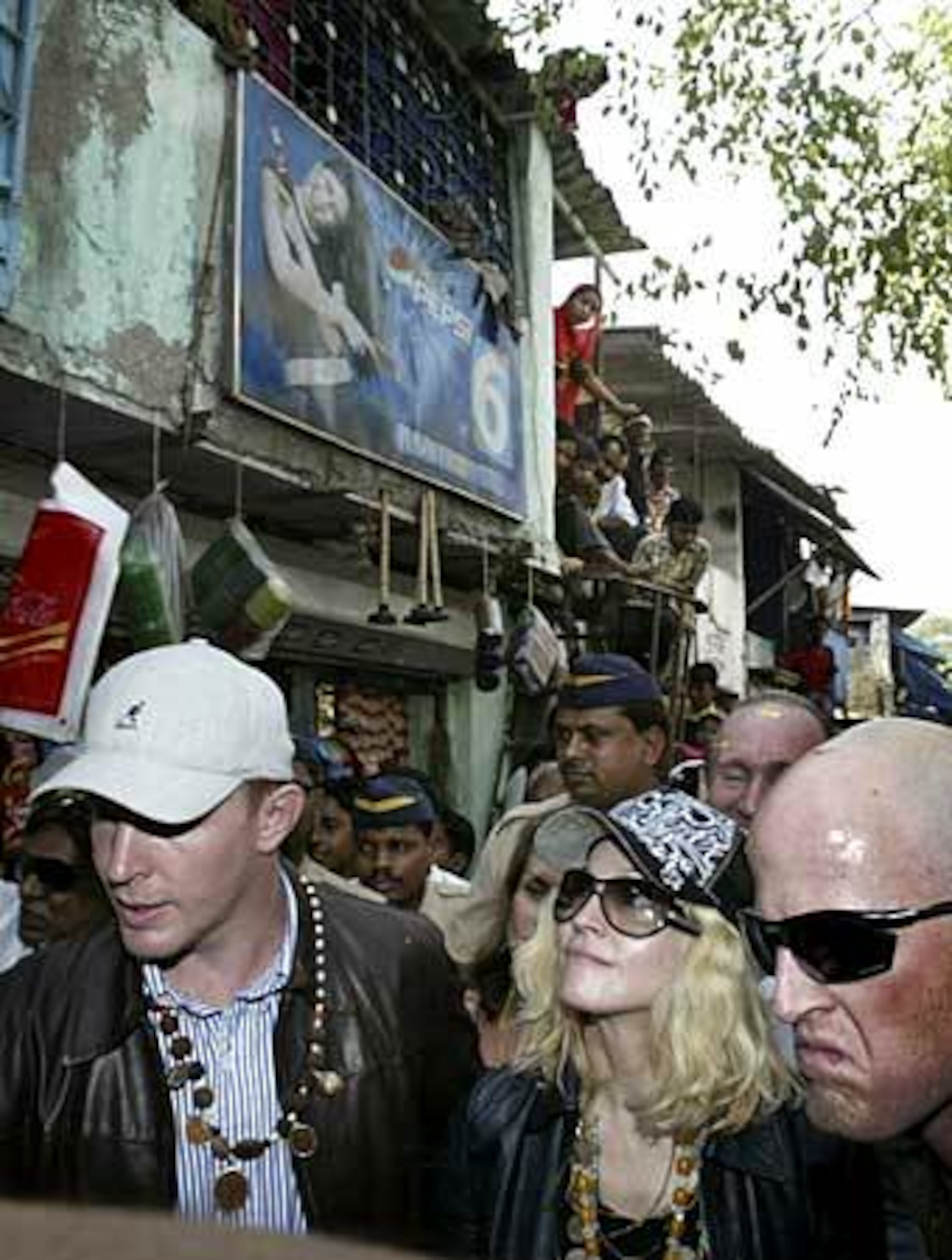Madonna's party and a few soldiers walk past a building topped with a poster depicting Indian Bollywood actor Kareena Kapoor.