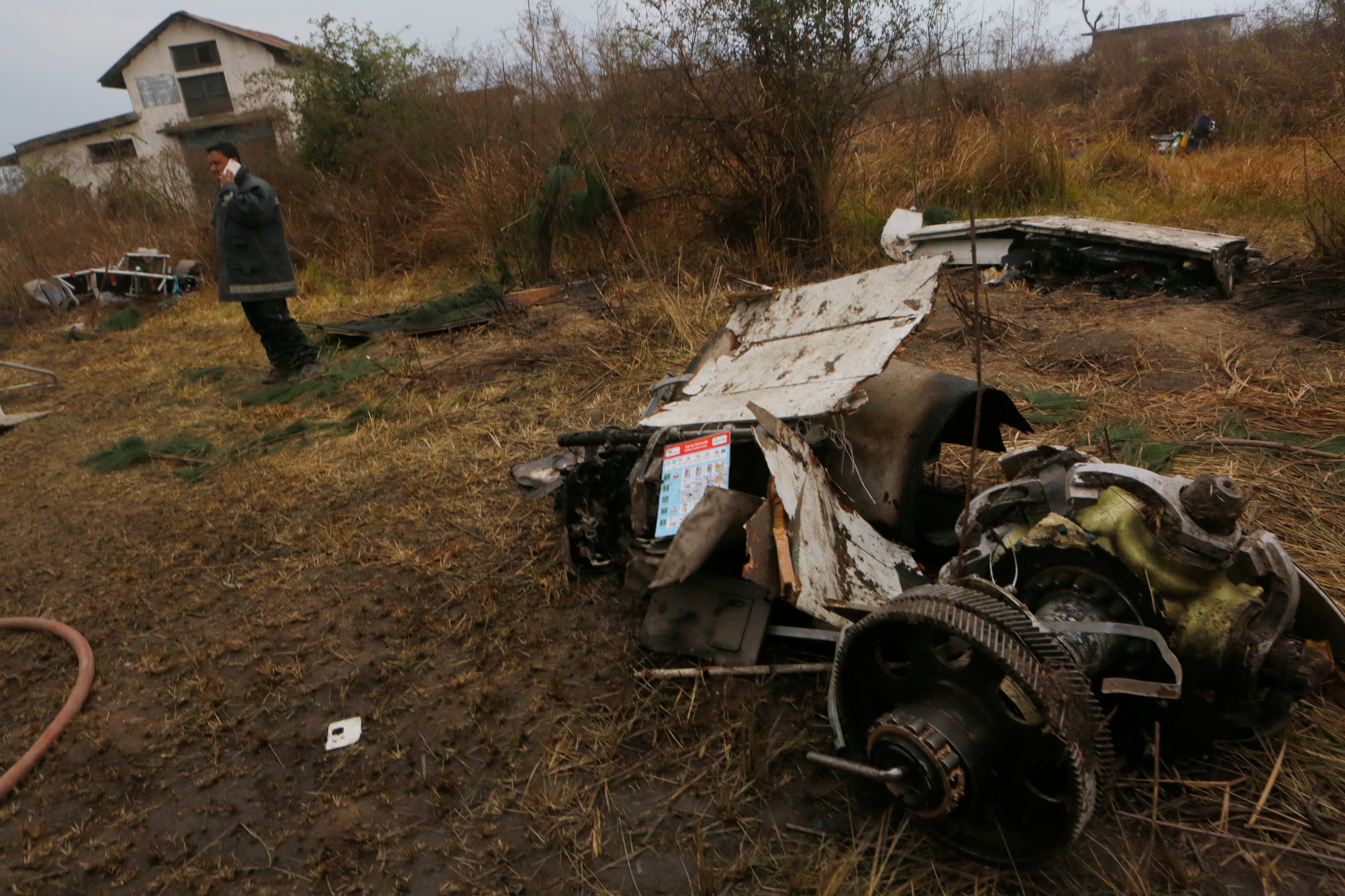 A Nepalese rescue worker stands near the debris after a passenger plane from Bangladesh crashed at the airport in Kathmandu, Nepal, Monday, March 12, 2018. The passenger plane carrying 71 people from Bangladesh crashed and burst into flames as it landed Monday in Kathmandu, Nepal's capital, killing dozens of people, officials said. (AP Photo/Niranjan Shreshta)