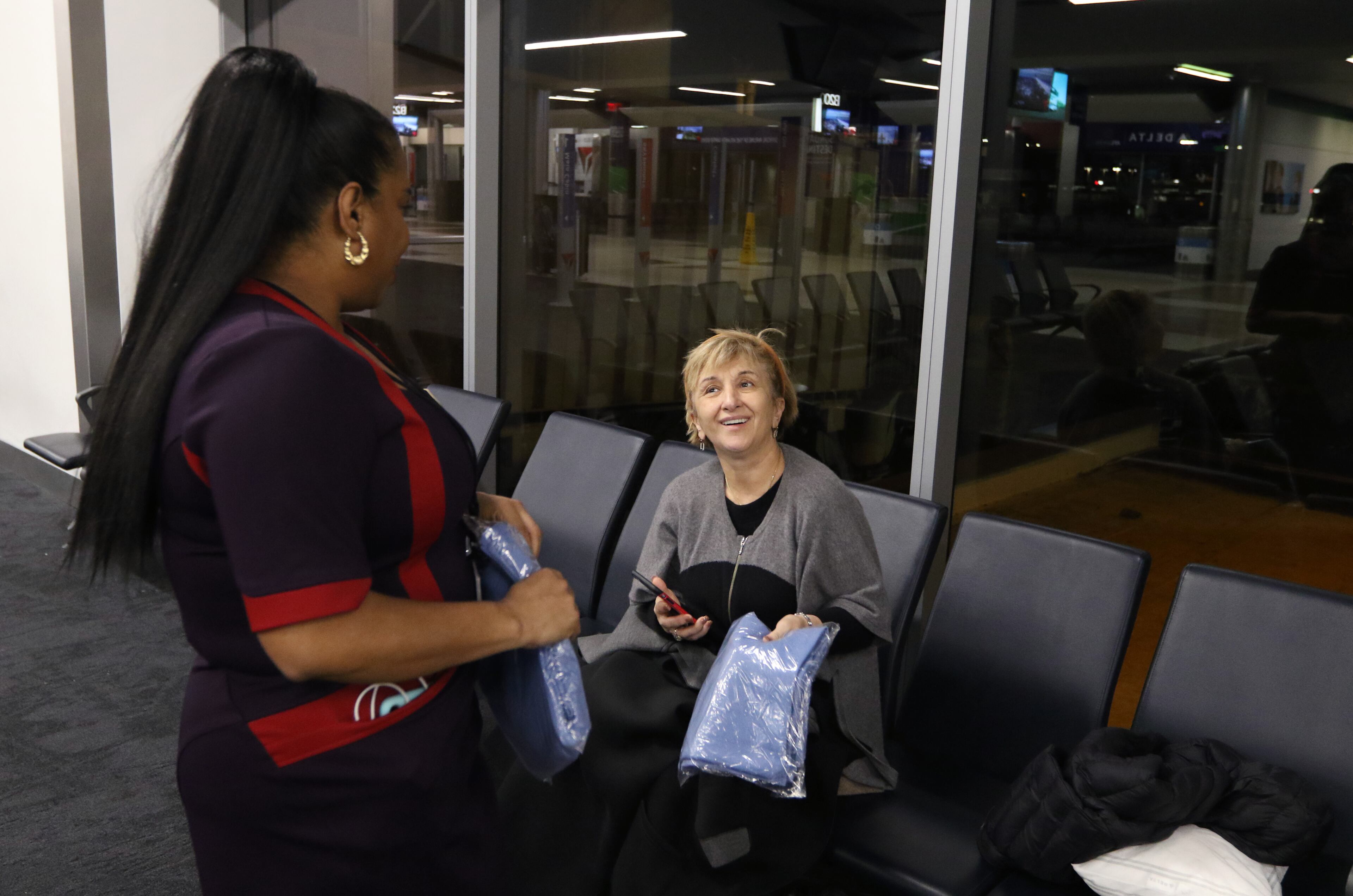 2/4/19 - Atlanta - Summer, a Delta Airlines employee, left, hands out blankets to Manana Lapidus. Lapidus did not attend the Super Bowl, but she is grateful to have a blanket for the night she and her husband will spend at the airport. Due to the number of people in town for the Super Bowl, they were not able to get accommodations after a flight got delayed. Delta Airlines handed out blankets and pillows to passengers spending the night in the airport instead of getting a hotel room after the Super Bowl. EMILY HANEY / emily.haney@ajc.com