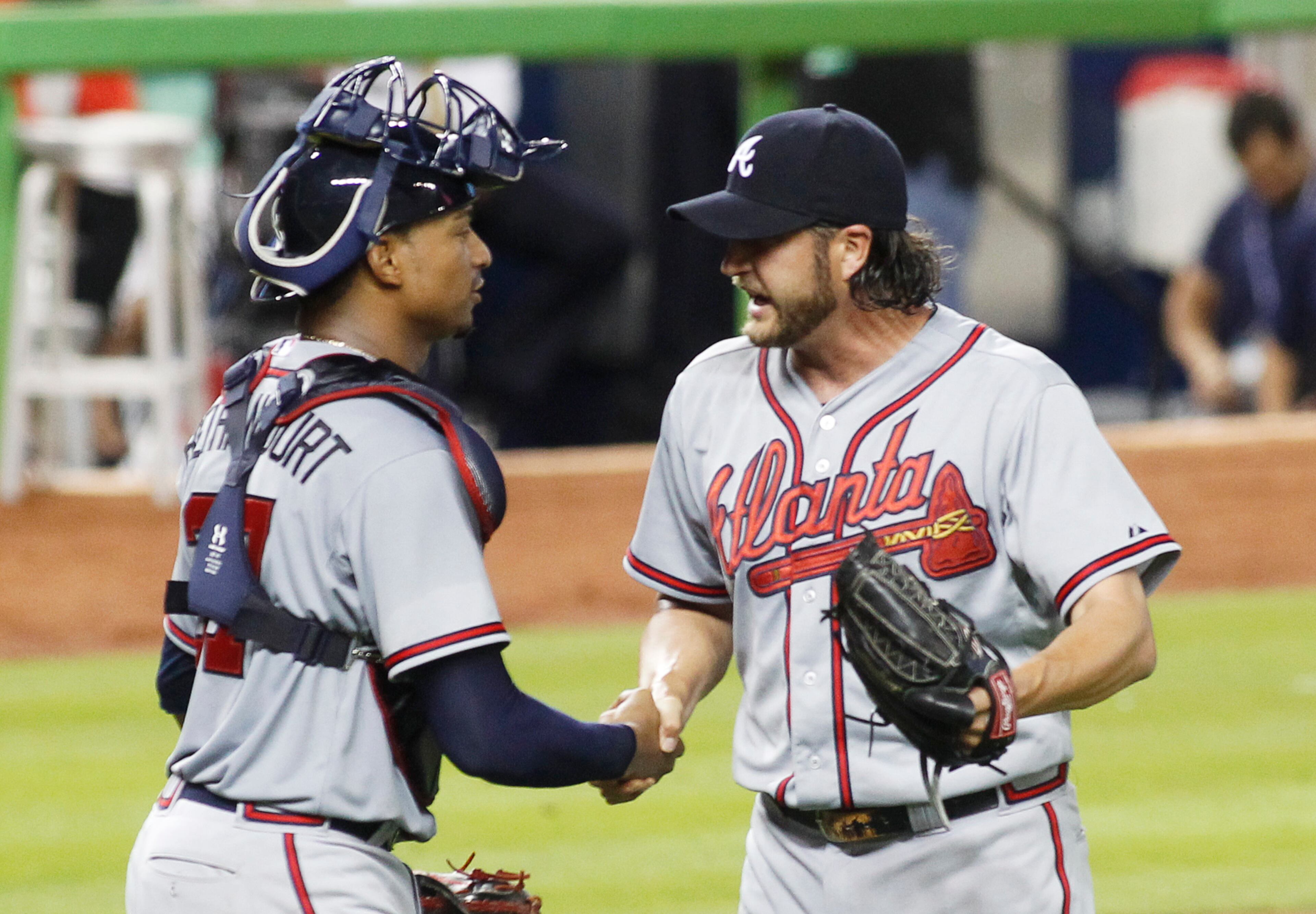 Atlanta Braves relief pitcher Jason Grilli celebrates his save with catcher Christian Bethancourt (27) after the Braves defeated the Marlins 2-1 in their opening day baseball game in Miami, Monday, April 6, 2015. (AP Photo/Joe Skipper)
