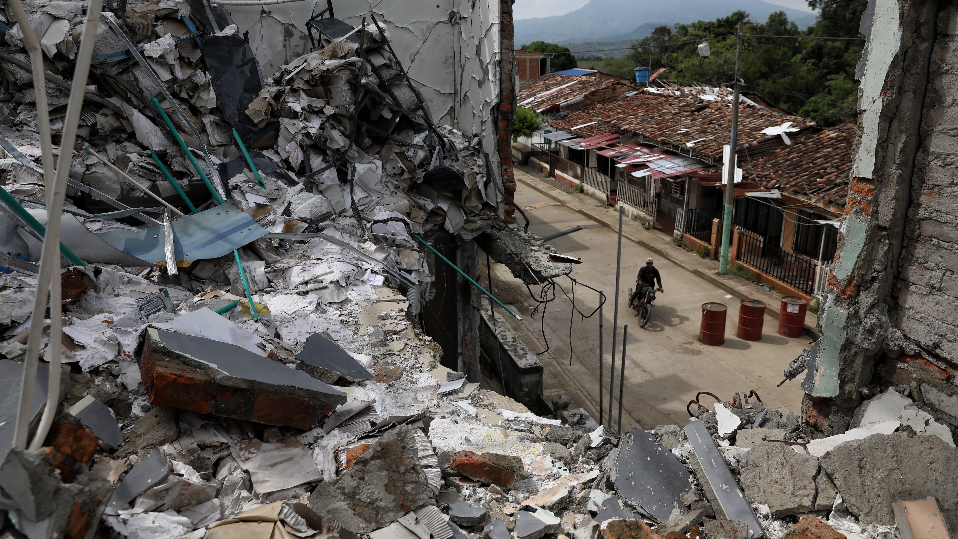 A man rides his motorcycle past the ruins of homes destroyed five months earlier in an attack by dissidents of the former Revolutionary Armed Forces of Colombia, or FARC, in Buenos Aires, Cauca, Colombia, Wednesday, May 20, 2026.(AP Photo/Santiago Saldarriaga)