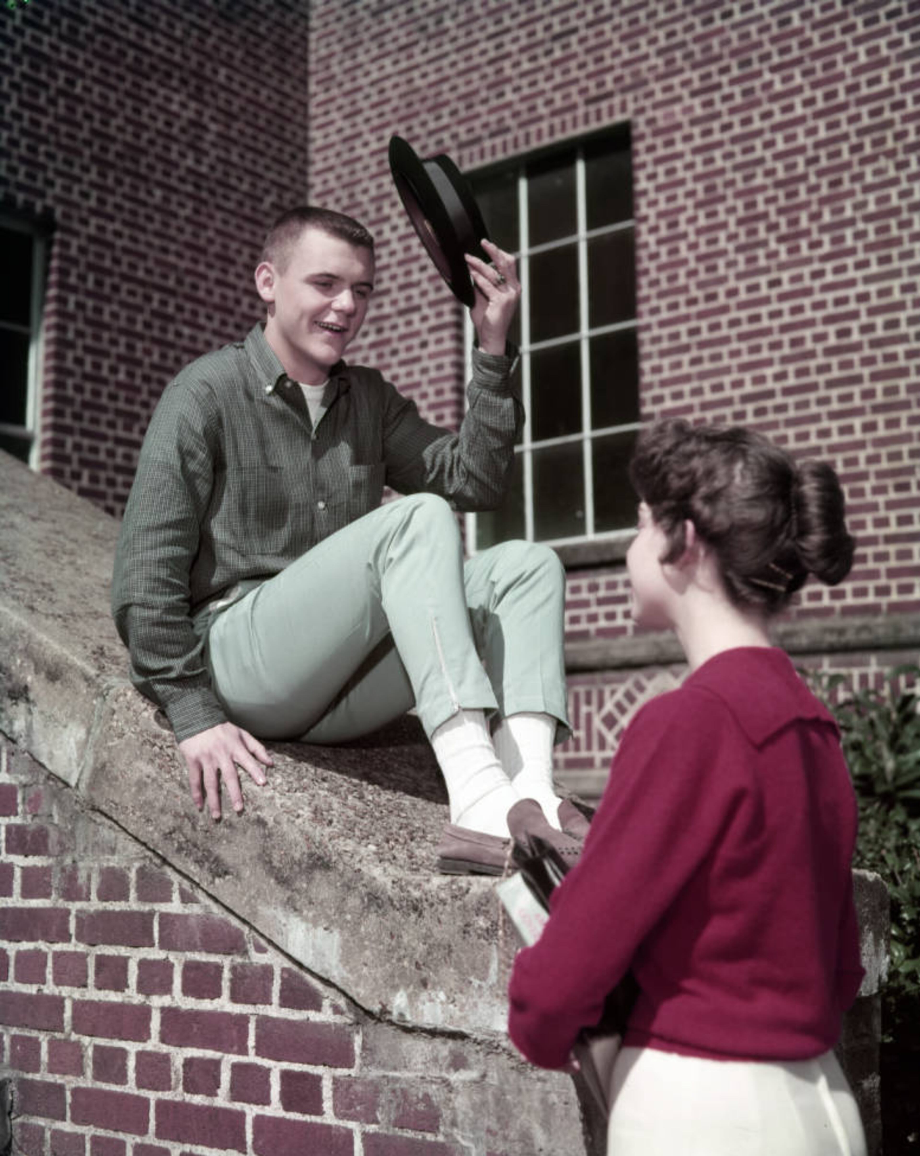 From the original caption info in 1959: ""O'Keefe senior Sonny Tolleson, decked out in pegged trousers, suede shoes and white socks, tips his lid to Beverly Roach. His haircut is a flattop."