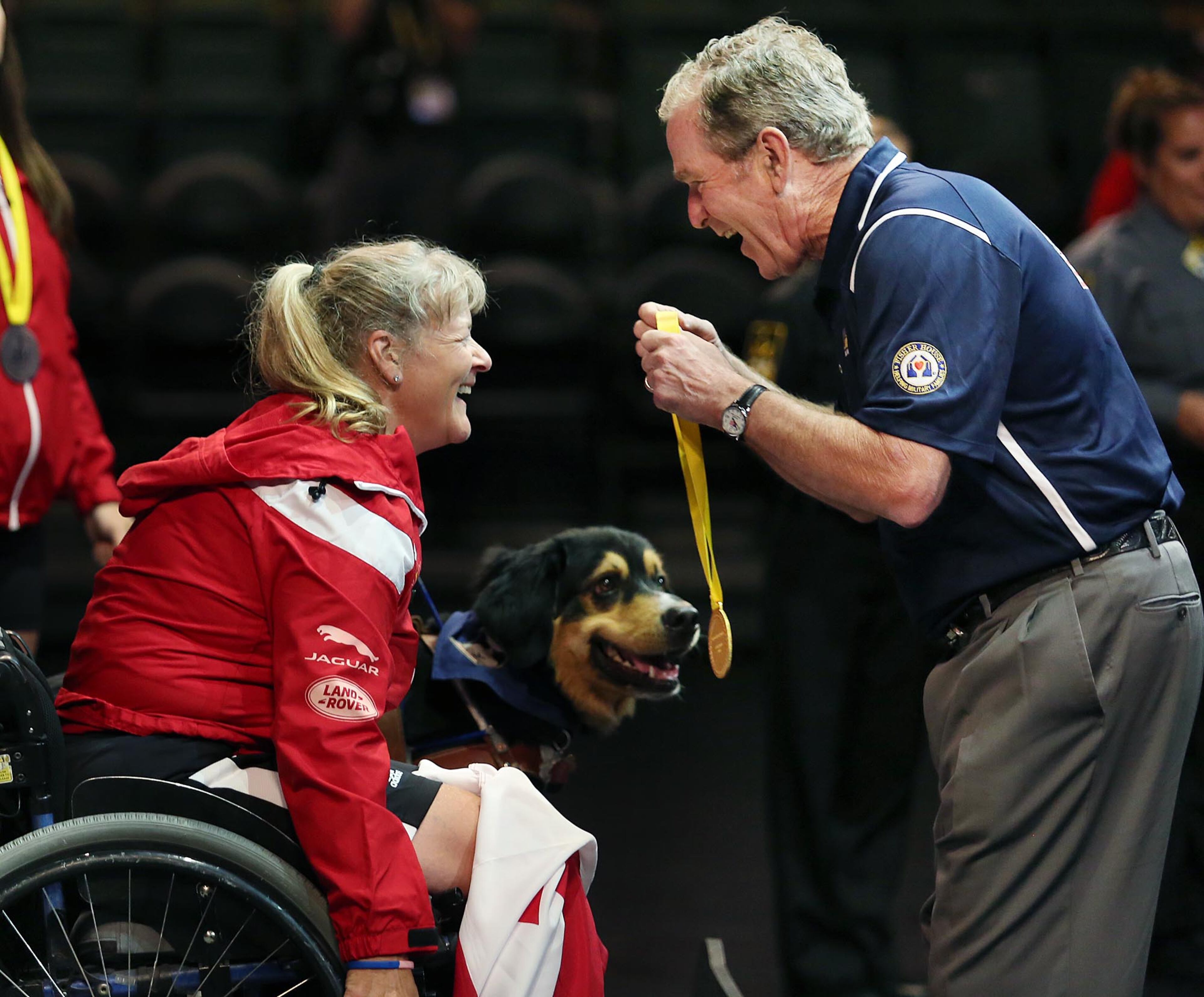 Former President George W. Bush, right, presents a gold medal in women's powerlifting to Canada's Christine Gauthier at the Invictus Games at Disney's ESPN Wide World of Sports, Monday, May 9, 2016, in Orlando, Fla. (Stephen M. Dowell/Orlando Sentinel via AP)
