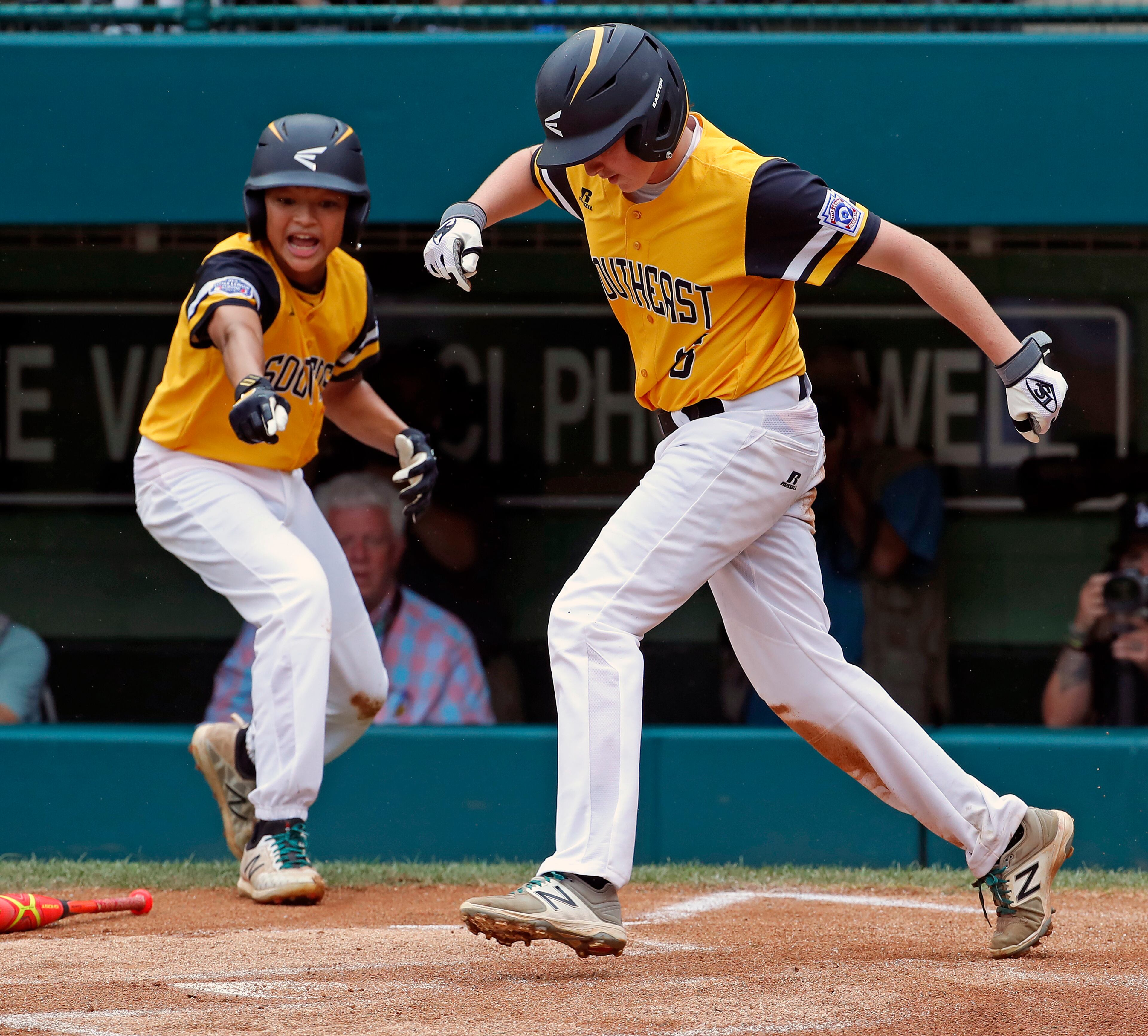 Peachtree City, Georgia's Jansen Kenty, right, leaps to tag home plate after scoring along with Tai Peete , left, on a single by Jack Ryan off Grosse Pointe Woods, Michigan's Brennan Hill (19) in the first inning of an elimination baseball game in United States pool play at the Little League World Series tournament in South Williamsport, Pa., Wednesday, Aug. 22, 2018. (AP Photo/Gene J. Puskar)