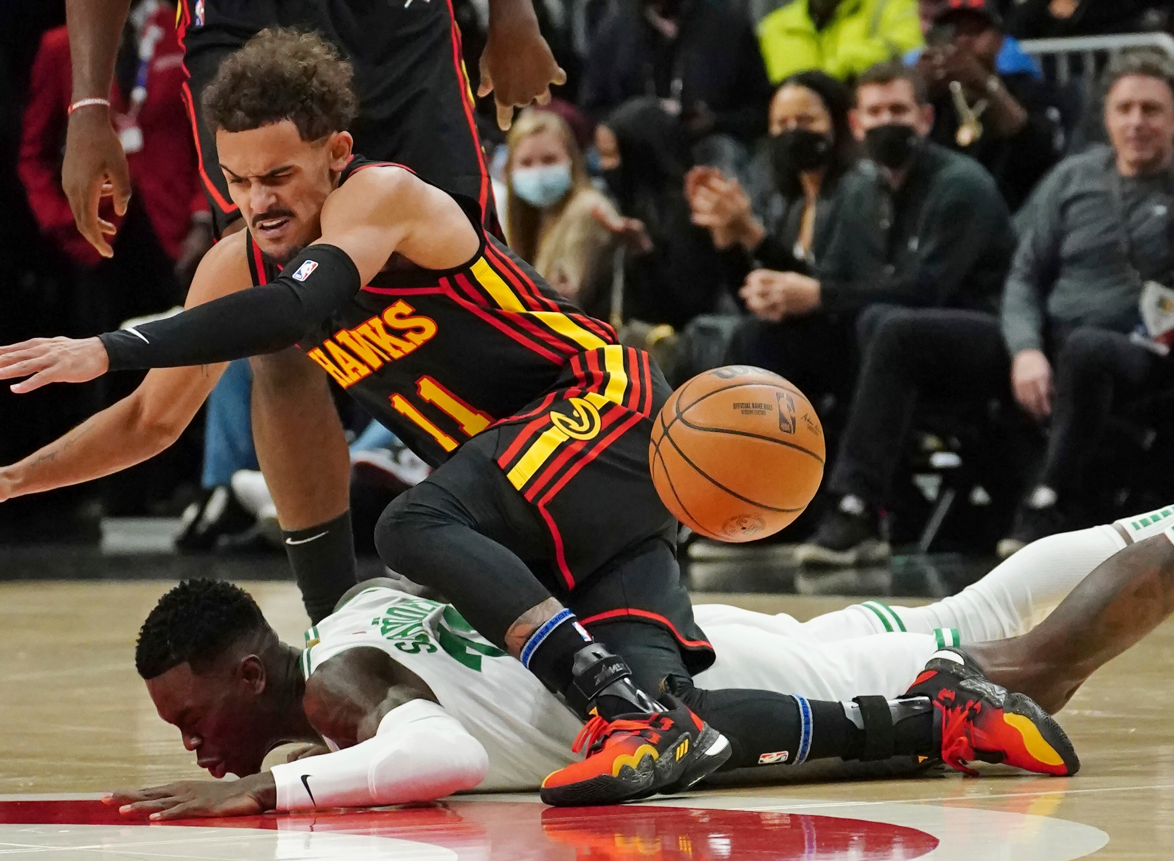 Atlanta Hawks guard Trae Young (11) and Boston Celtics guard Dennis Schroder (71) scramble for a loose ball in the first half of an NBA basketball game. (AP Photo/John Bazemore)