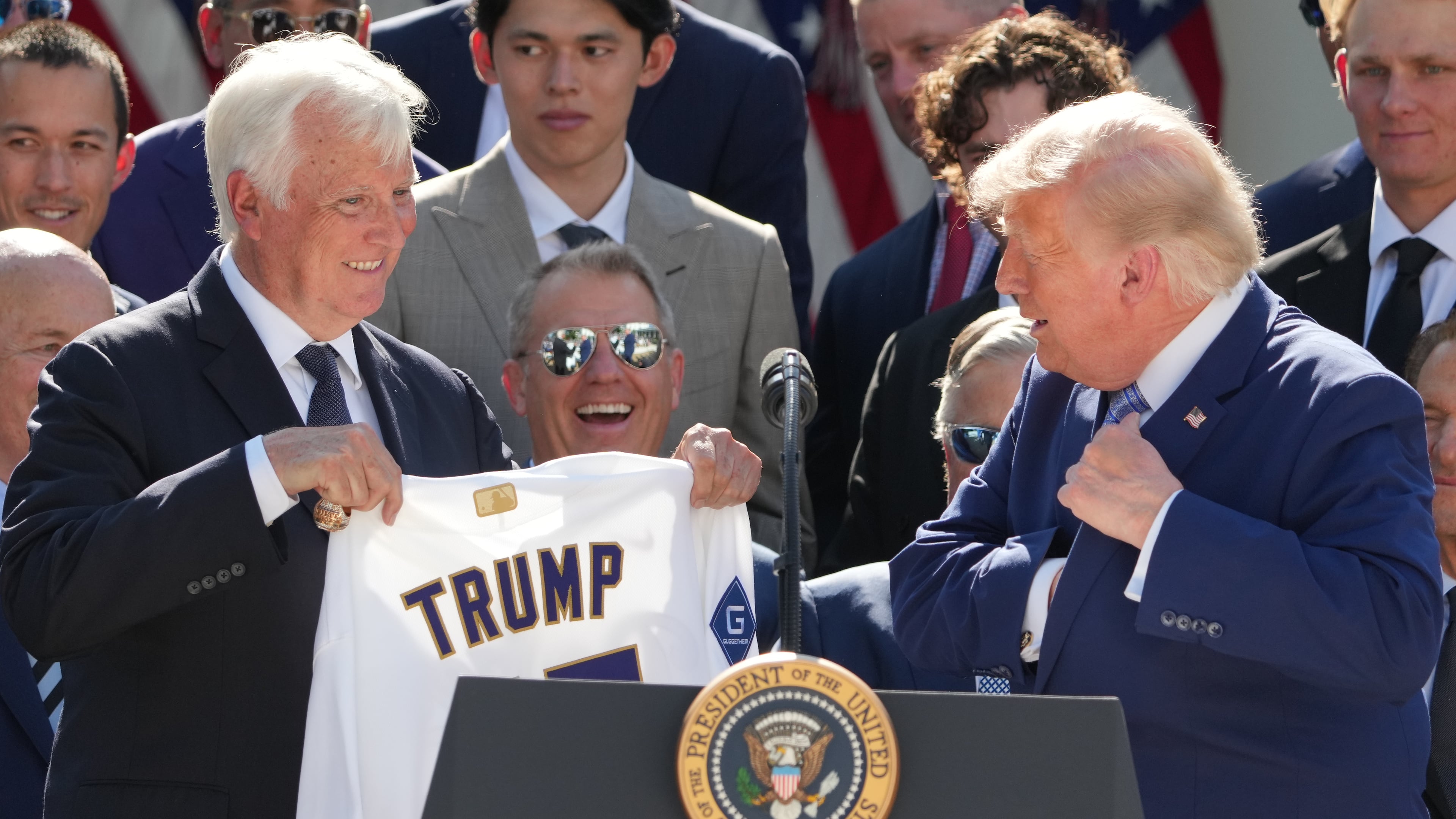 President Donald Trump puts a championship ring into his pocket as owner Mark Walter presents him with a jersey during an event to honor the 2025 World Series champions Los Angeles Dodgers in the Rose Garden of the White House, Thursday, July 23, 2026, in Washington. (AP Photo/Alex Brandon)
