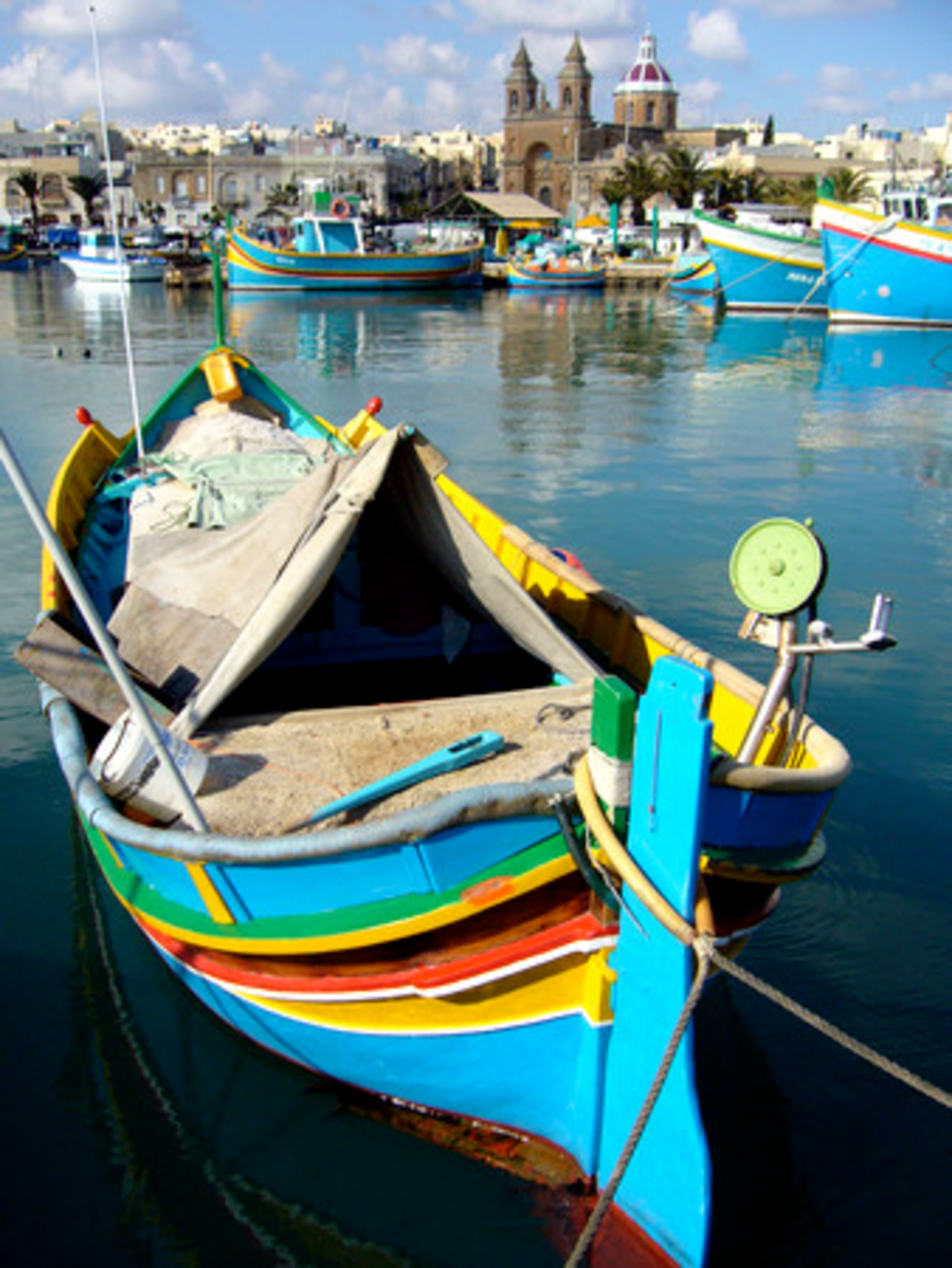 Brightly colored fishing boats known as luzzus fill the harbor in Marsaxlokk, the largest fishing village in Malta. The village is a popular place for tourists seeking fresh seafood.