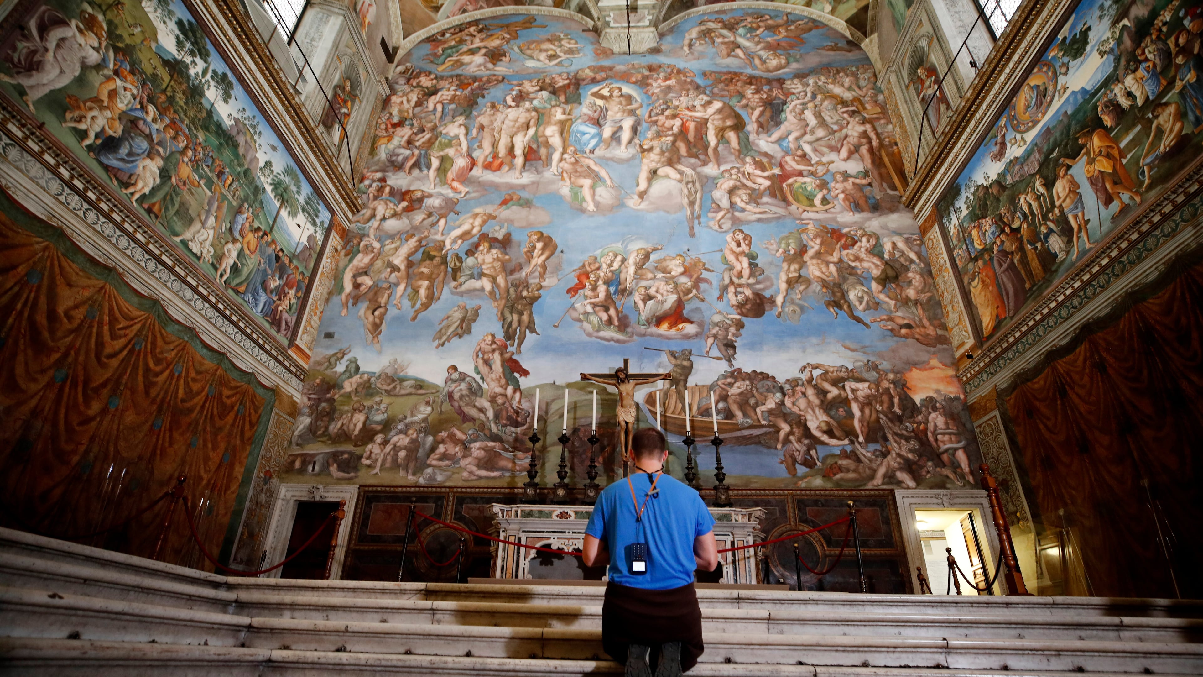 FILE - A visitor kneels in front of the Last Judgement fresco by the Italian Renaissance painter Michelangelo inside the Sistine Chapel in Rome, May 3, 2021. (AP Photo/Alessandra Tarantino, File)