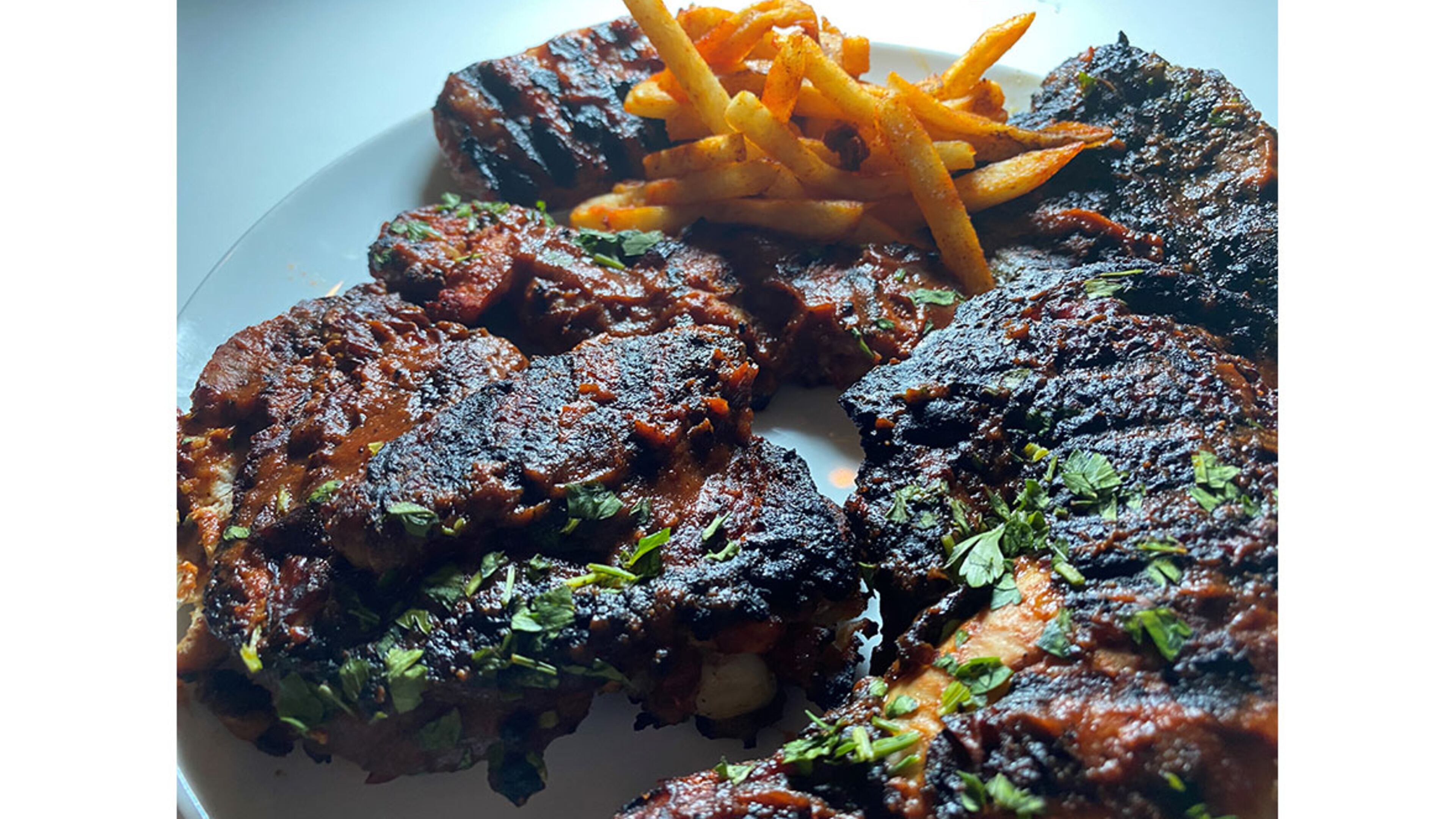 The Asado Mixto platter includes grilled chicken, chorizo, beef, and guava shrimp, with sauces and fries. /
Bob Townsend for the Atlanta Journal-Constitution