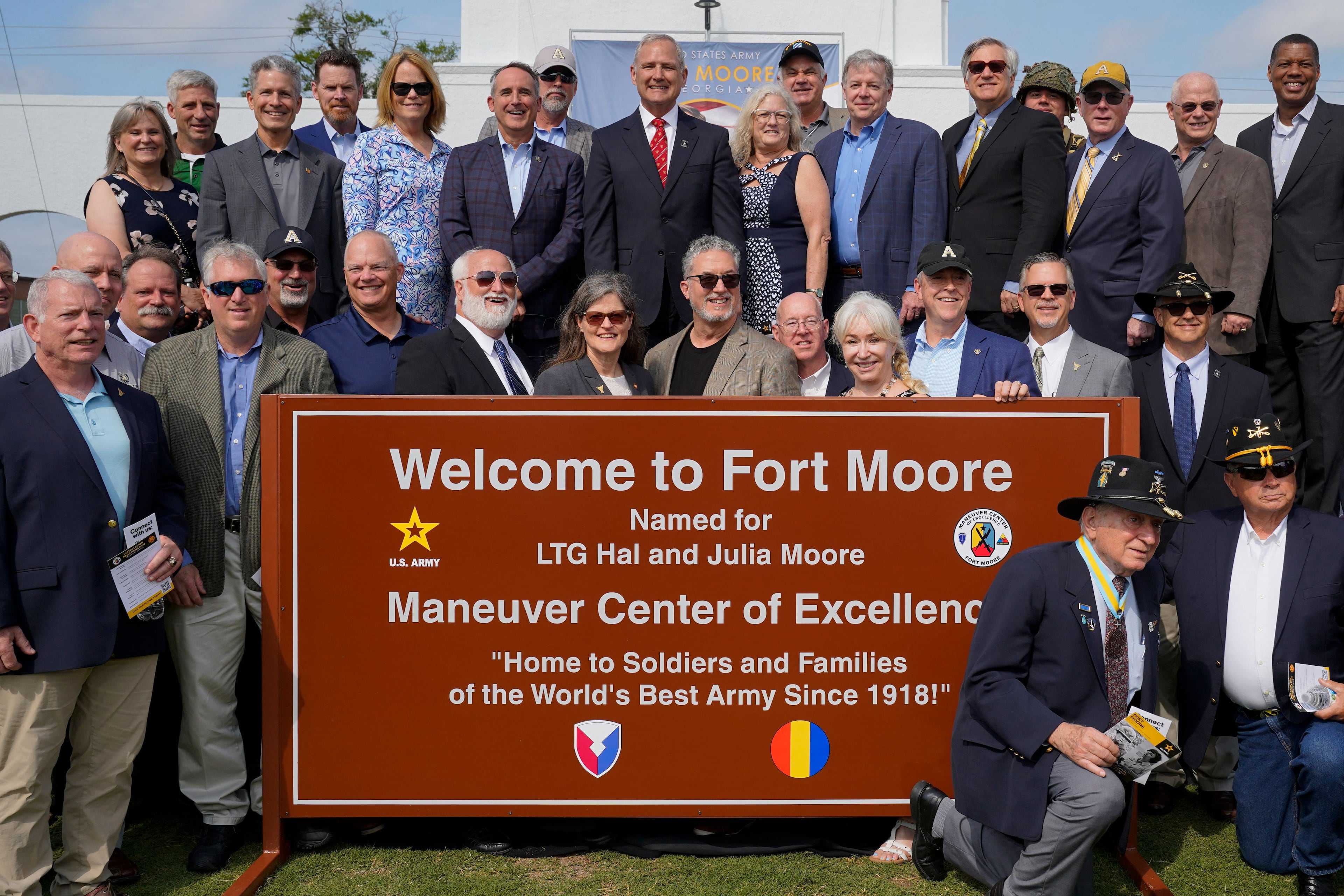 People pose for photos next to a newly unveiled Fort Moore sign during a ceremony to redesignate Fort Benning as Fort Moore, at Doughboy Stadium in Columbus, Georgia, on May 11, 2023. (Photo by CHENEY ORR / AFP) (Photo by CHENEY ORR/AFP via Getty Images)