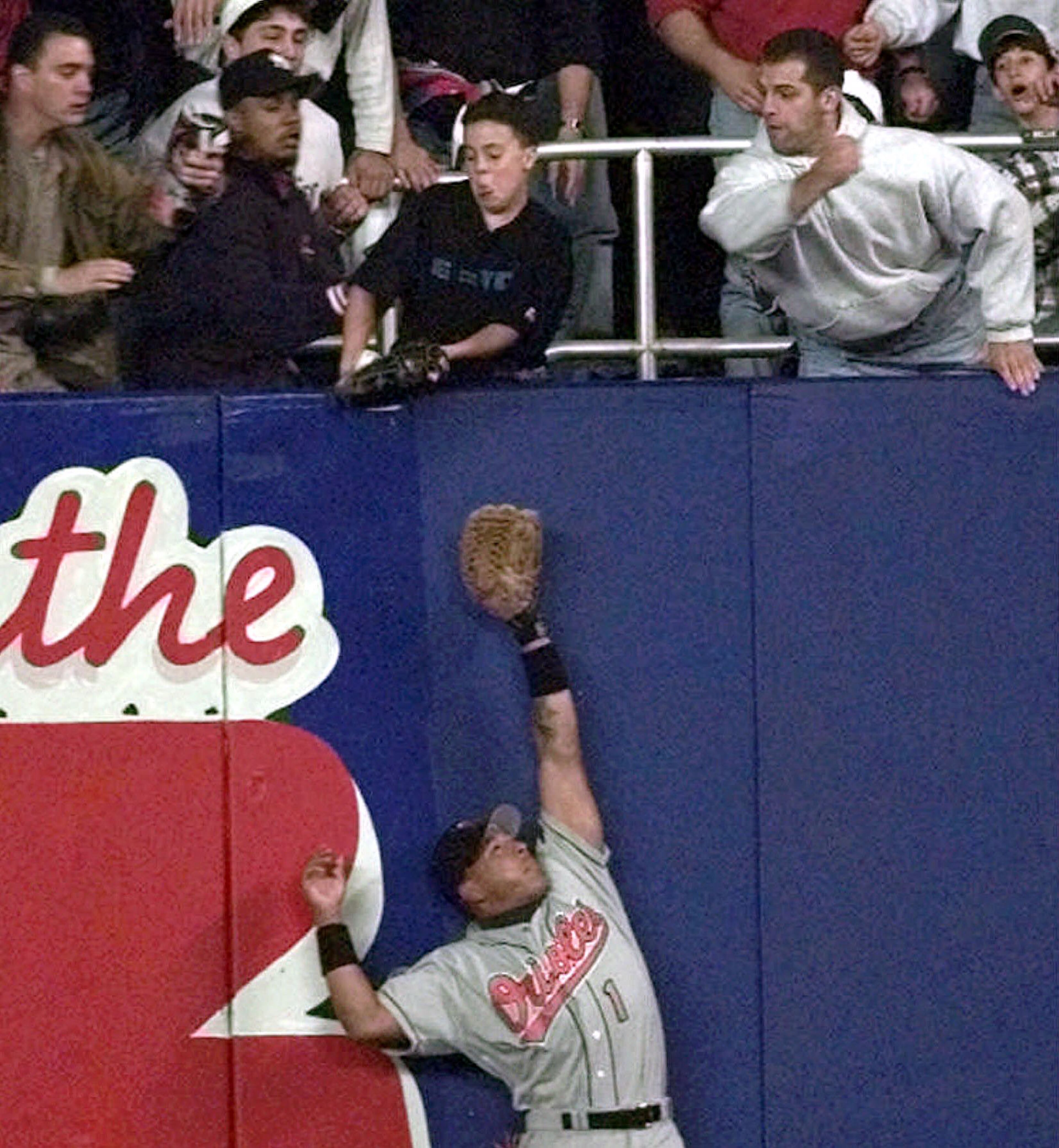 FILE - In this Oct. 9, 1996, file photo, Baltimore Orioles' right fielder Tony Tarasco stretches for the ball as young Yankee fan Jeff Maier deflects it during Game 1 of the American League Championship Series against the New York Yankees in New York. The ALCS opener against Baltimore, Derek Jeter hits an eighth-inning drive to right field at Yankee Stadium. A young fan reaches out and gets his glove on the ball, pulling it over the fence for a tying homer that turns 12-year-old Jeffrey Maier into an instant celebrity. The Orioles are livid, but umpire Rich Garcia does not rule fan interference, this was long before instant replay in baseball. New York goes on to win the game, and eventually its first World Series title in 18 years. (AP Photo/Mark Lennihan, File)