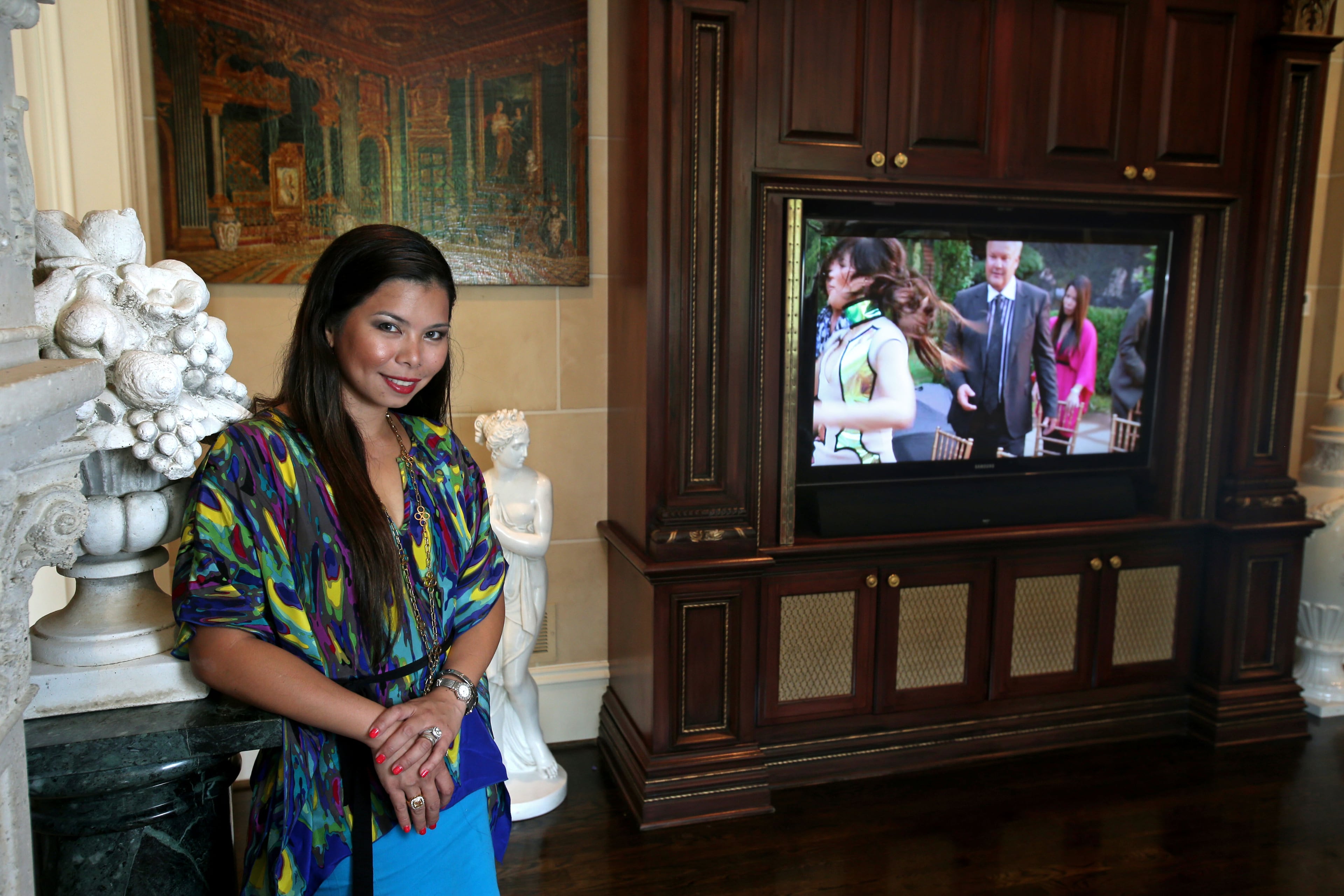 Livia Hostetler stands near her television. She's paused a scene of the show "Single Ladies," where she and her husband Scott were extras in a scene where a fight breaks out and actors end up falling into their swimming pool.